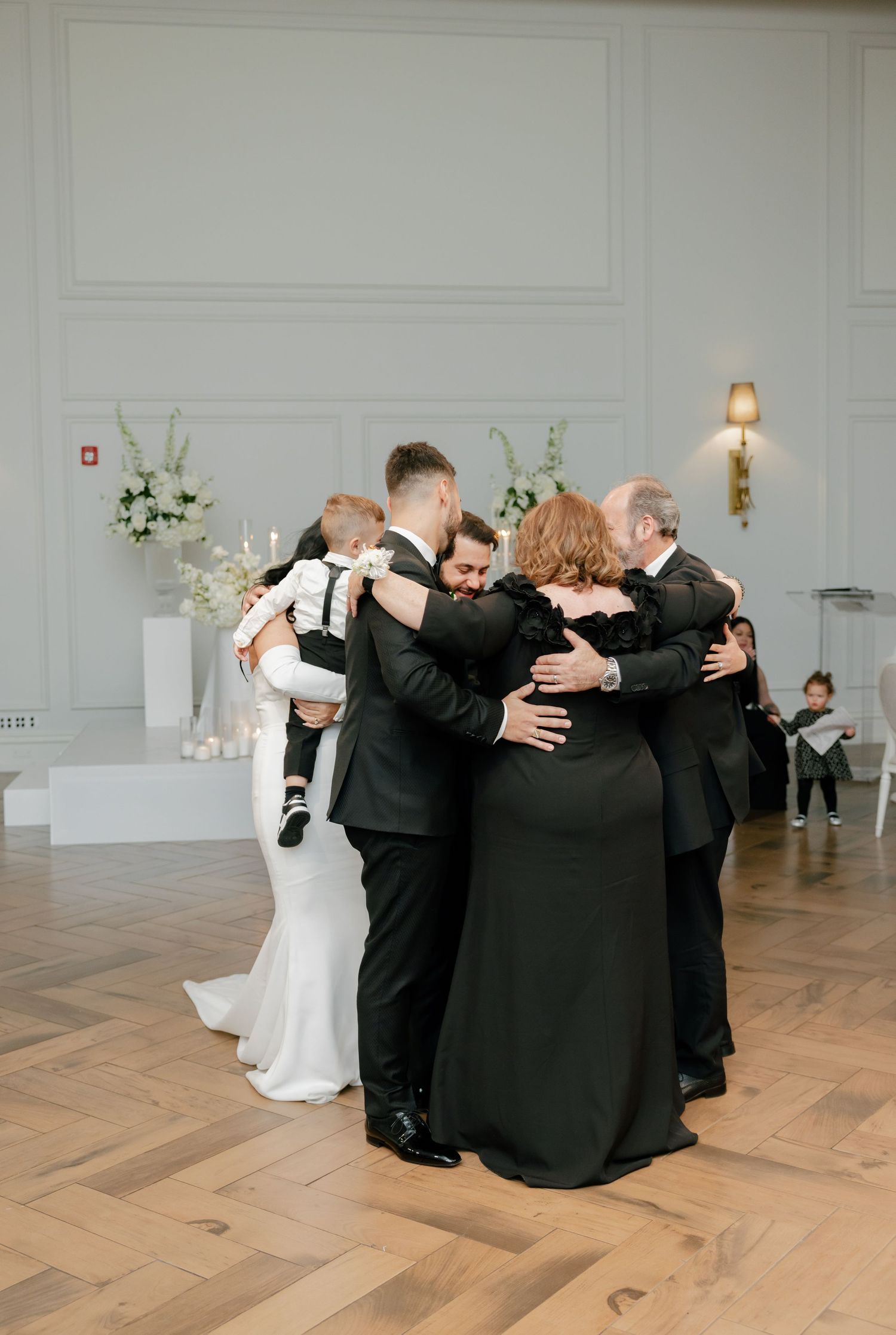 Wedding guests share a group hug on the dance floor during an emotional reception moment.