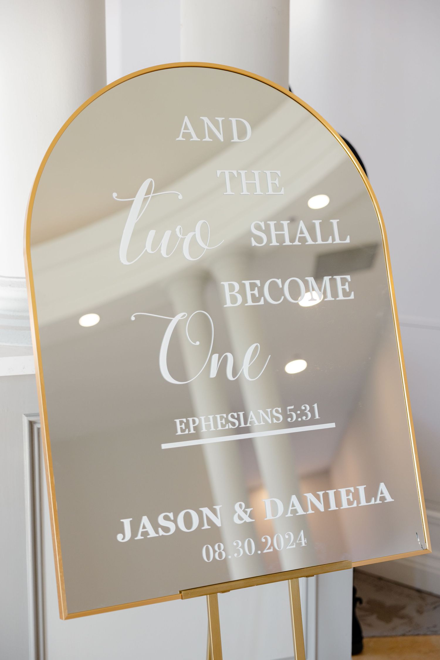 Gold-rimmed mirror sign displaying Ephesians 5:31 bible verse for wedding ceremony.