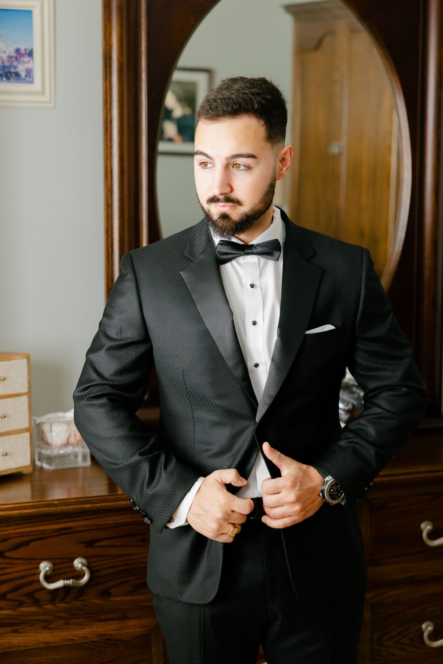 Elegant black tuxedo and bow tie ensemble showcased against wooden furniture background.