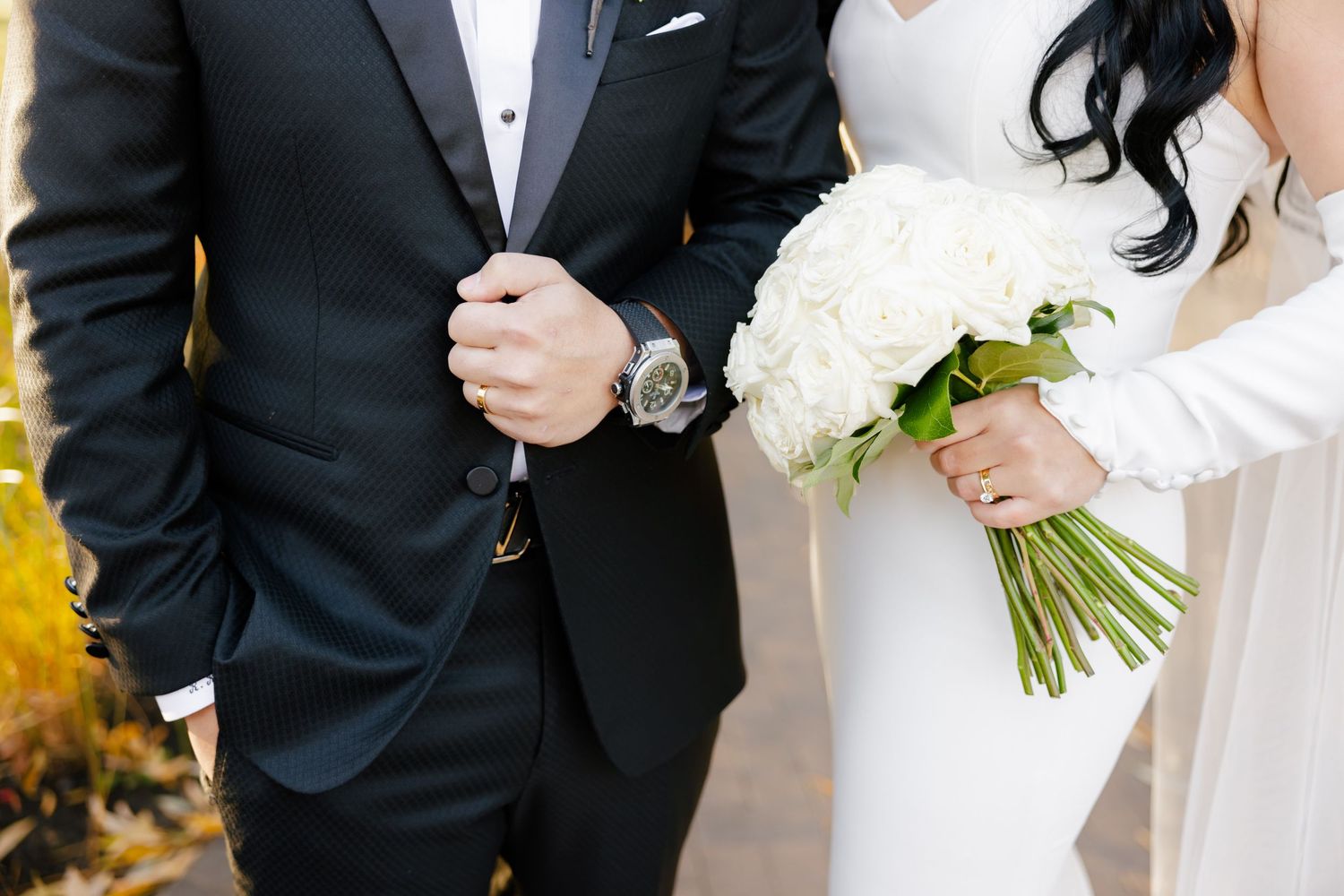 Close up detail of formal wedding attire and white rose bouquet.