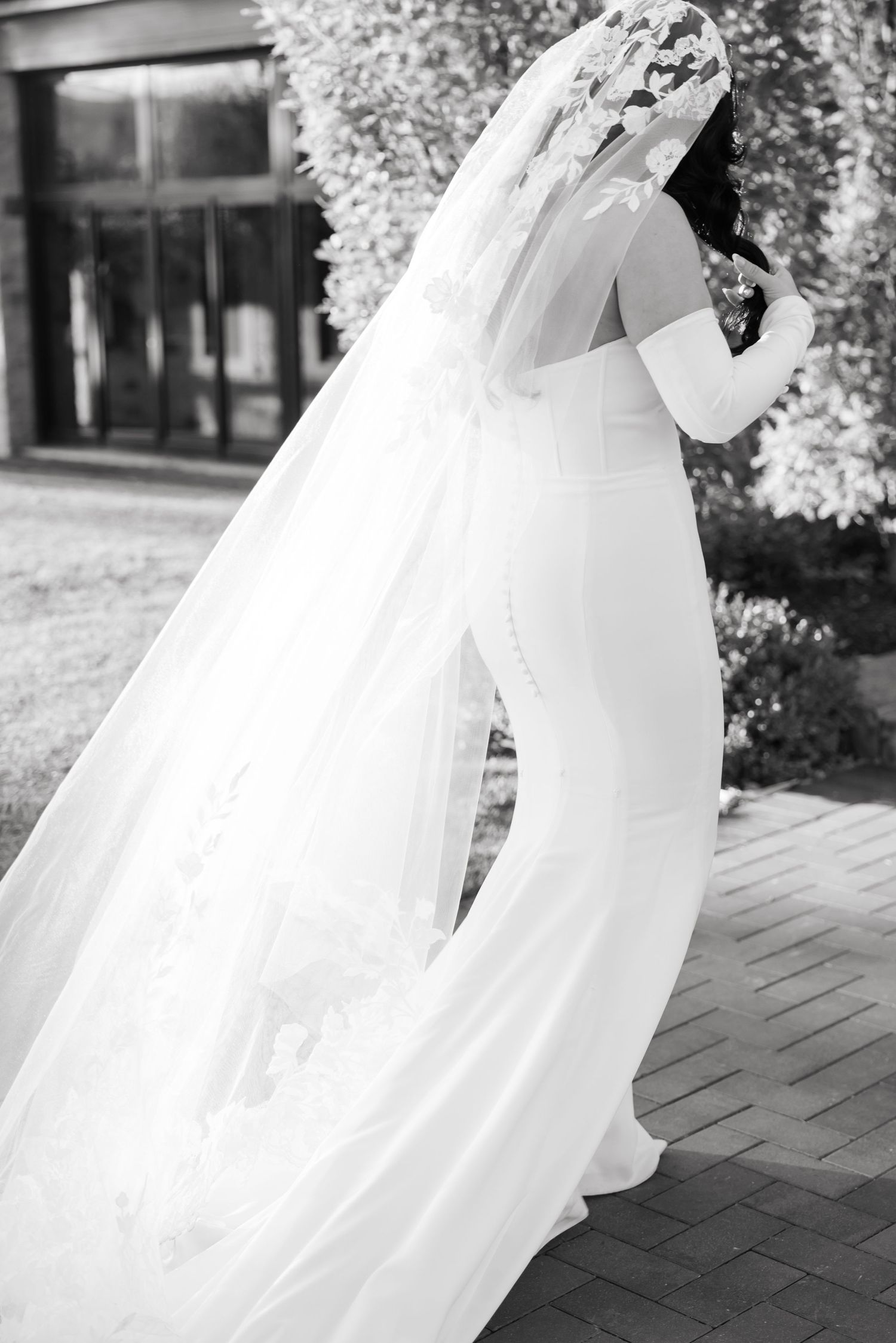 Elegant bridal gown and veil flow in gentle breeze during outdoor wedding.
