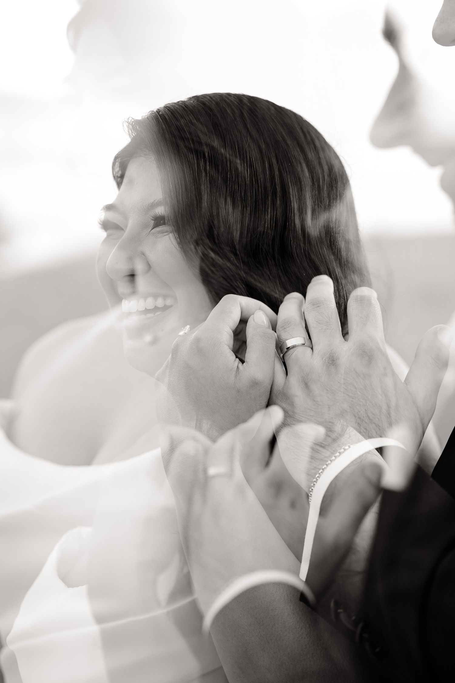 Black and white close-up of gentle moment showing wedding rings and embracing hands.