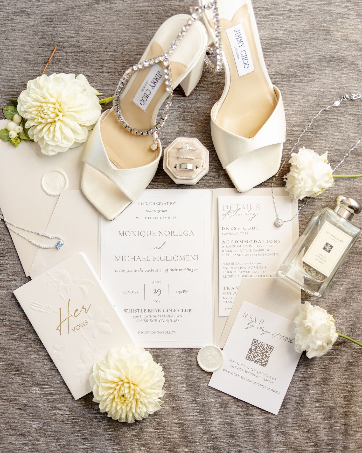 Wedding details including white heels, stationery and Jo Malone fragrance arranged on gray background.