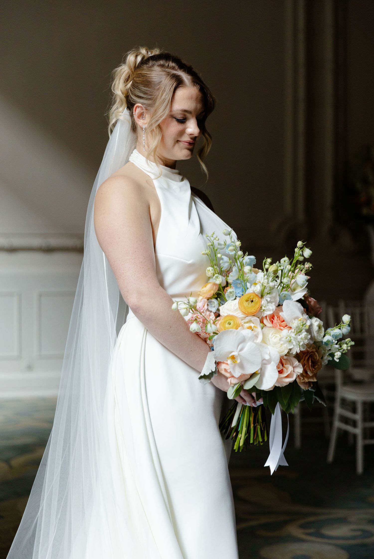 An elegant bridal bouquet features peach and white flowers with delicate greenery.