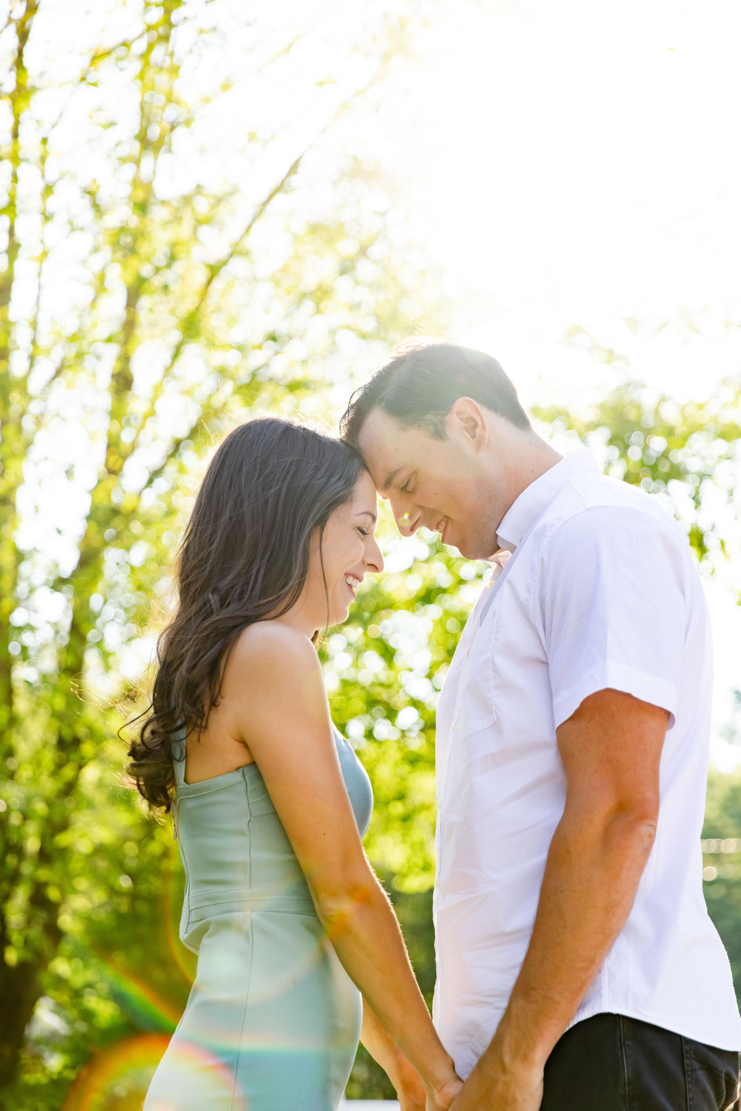 Couple sharing tender moment in sunlit forest setting.