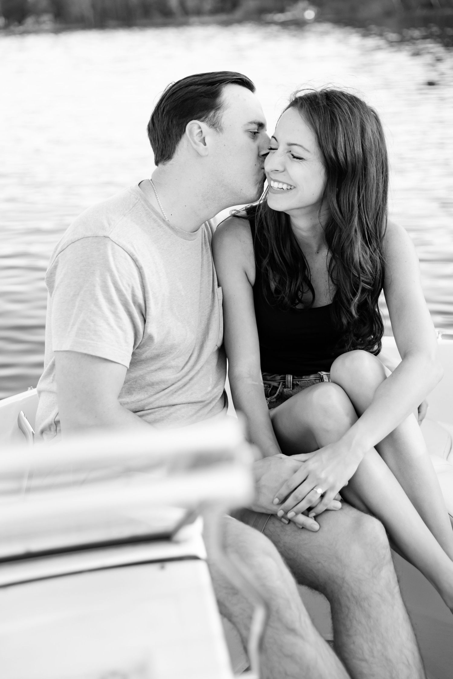 A black and white portrait of a couple sharing an intimate moment on a boat.