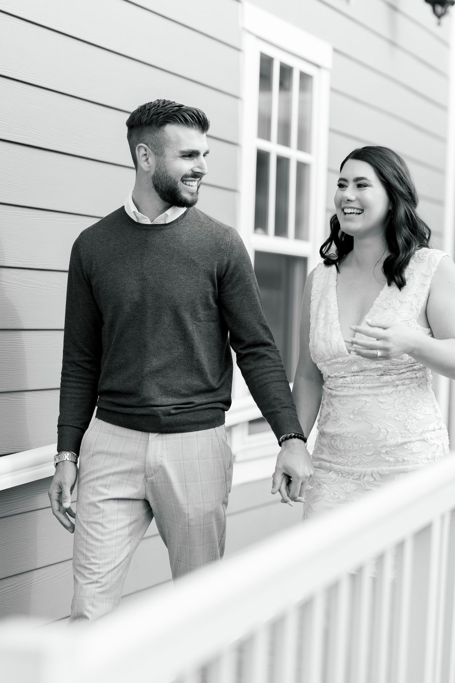 Casual portrait of two people on a white porch with beige siding.