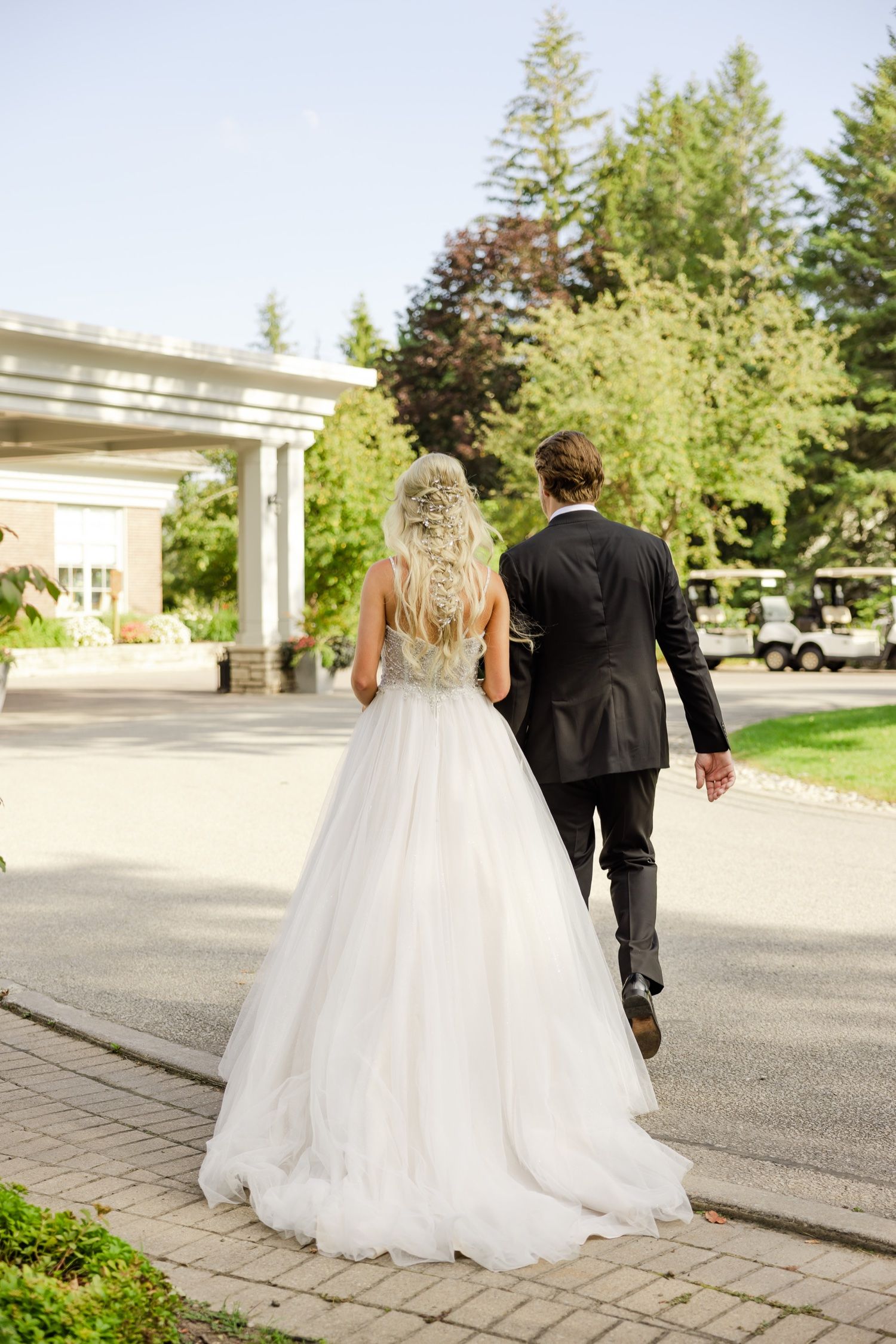 Wedding couple walks away on stone path revealing detailed back of bridal gown.