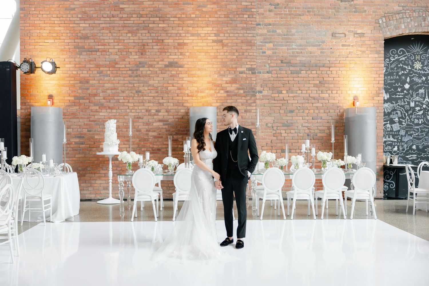 Modern wedding venue with exposed brick walls and elegant white table settings.