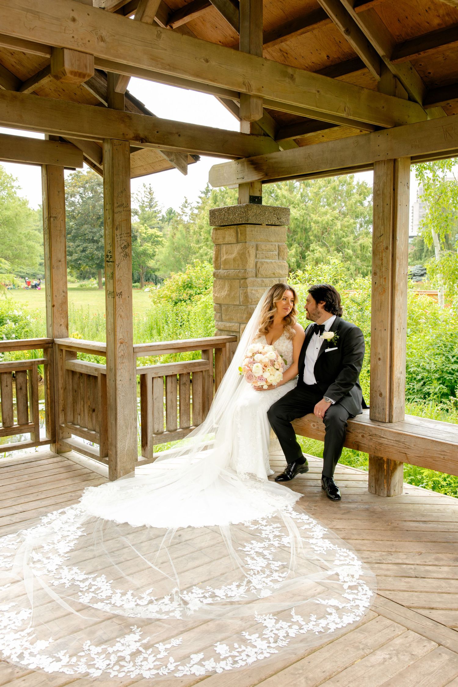 Wedding portrait in wooden gazebo showcasing ornate lace veil design.