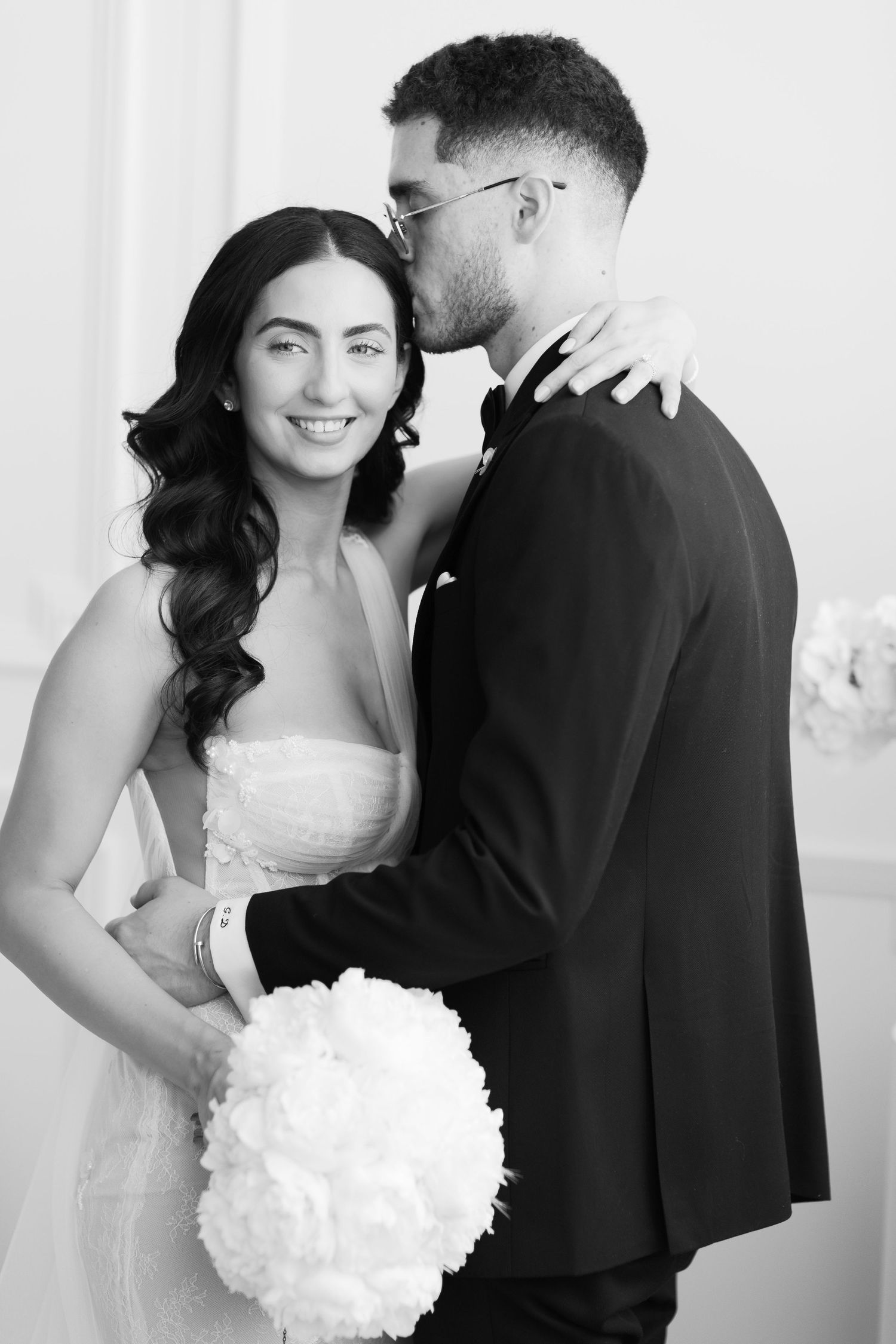 Black and white wedding portrait captures tender moment between couple.