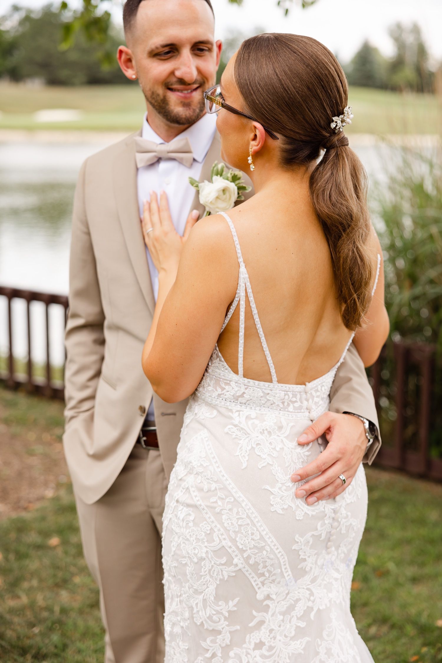 Close-up of couple sharing intimate moment outdoors, showcasing bride's detailed back of dress.