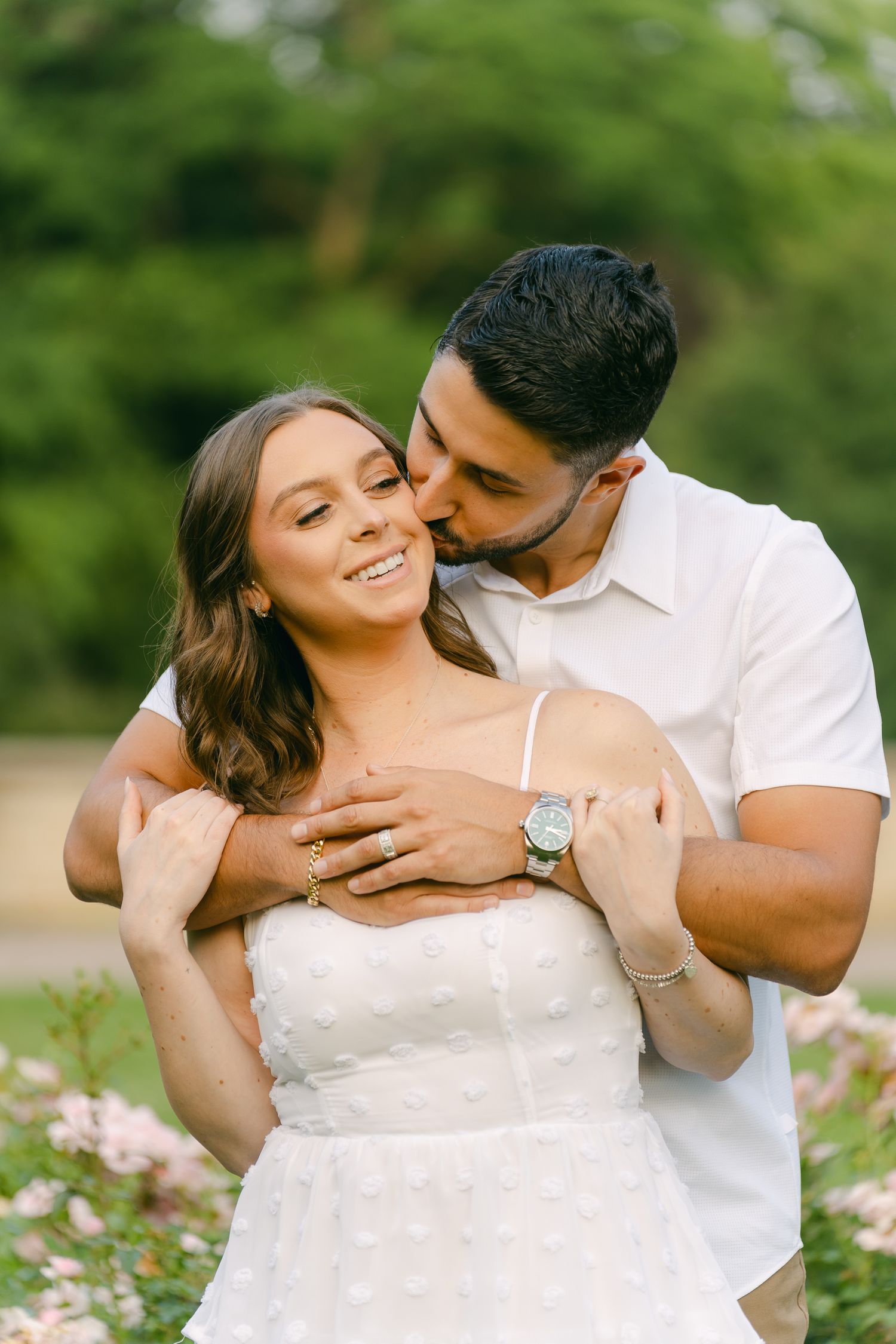 An intimate portrait of a couple sharing a romantic moment among blooming garden flowers.