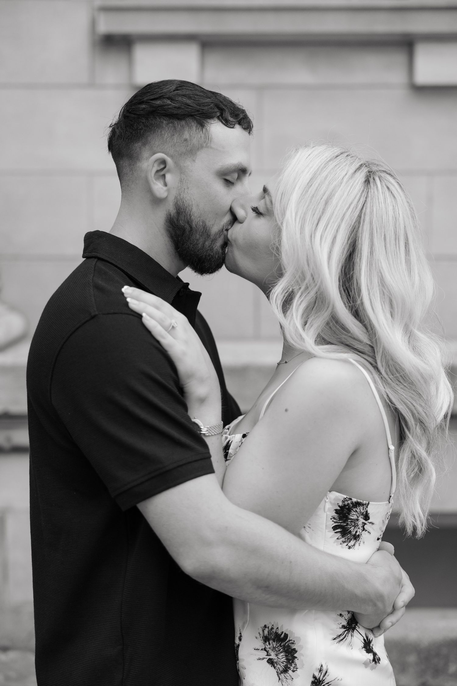 Black and white portrait of couple sharing romantic kiss outdoors.