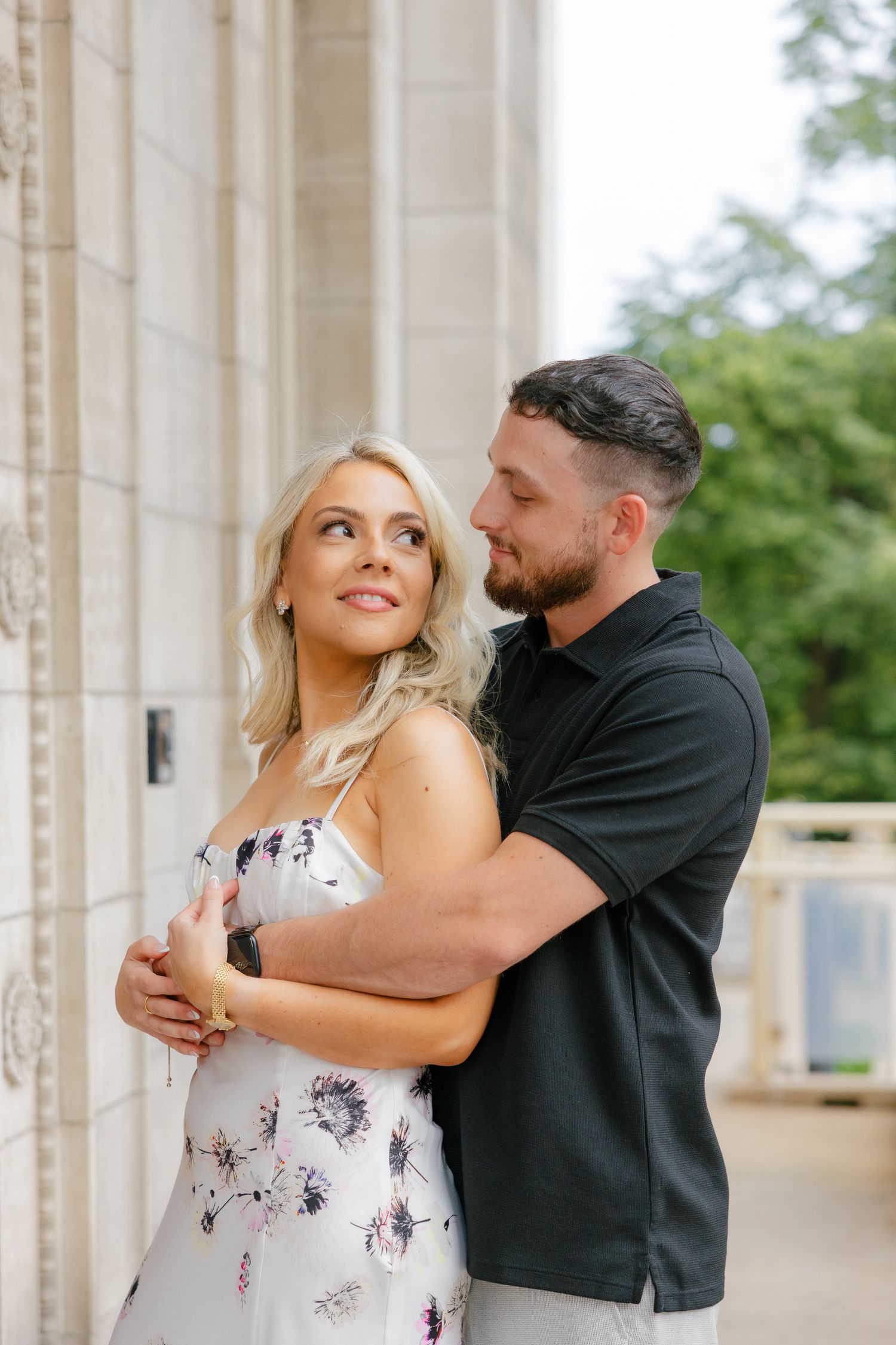 A couple shares an intimate moment while embracing between classical stone columns.