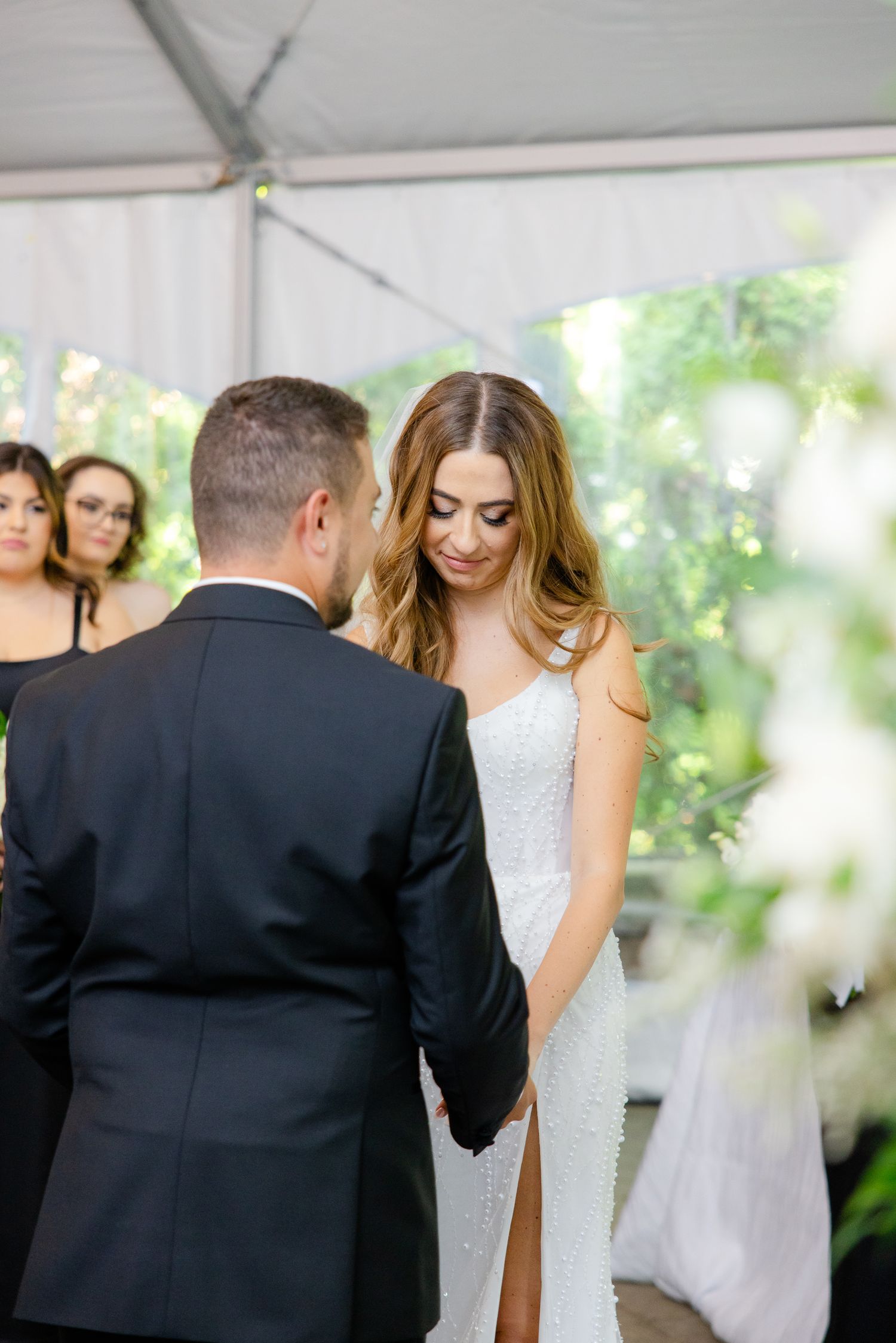 Intimate wedding ceremony moment between couple under white tent with natural lighting.