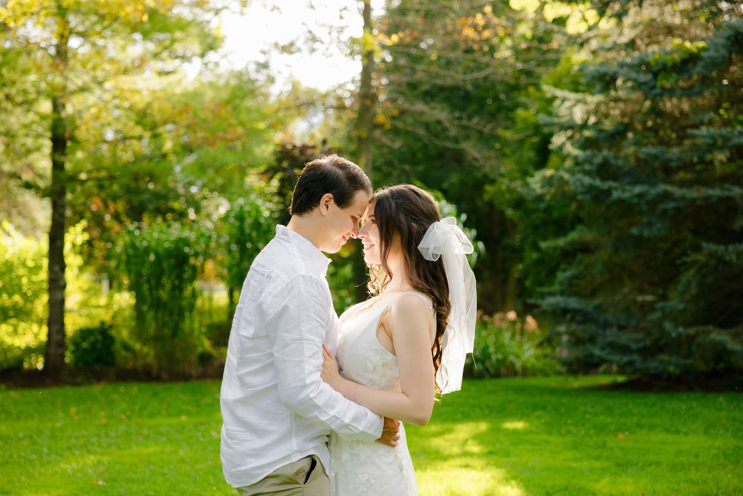 Romantic garden wedding portrait with golden sunlight filtering through trees.