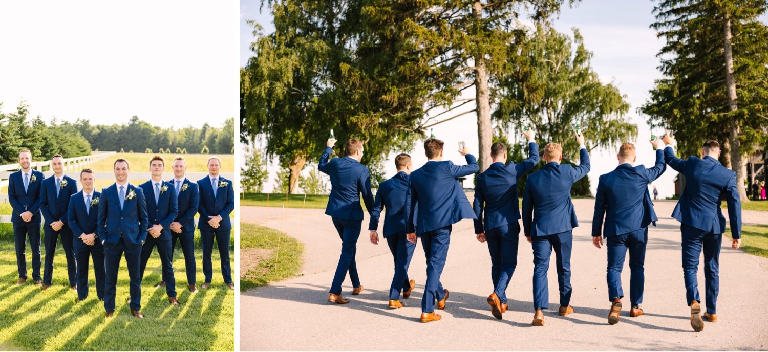 Wedding party in navy suits walks together along sunny outdoor path.