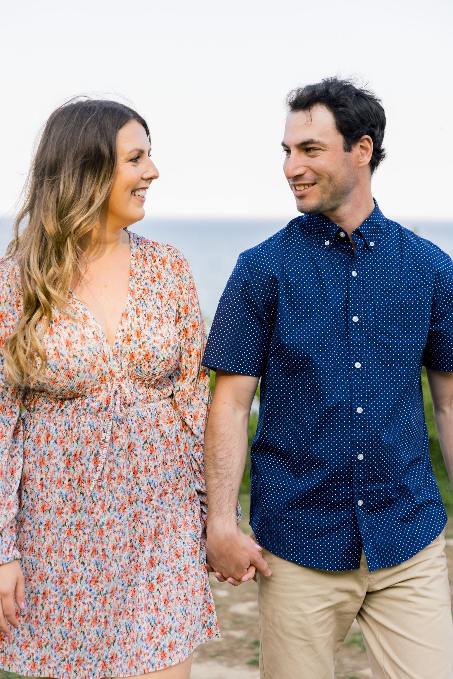 Couple in coordinating outfits share joyful laughter while holding hands outdoors.