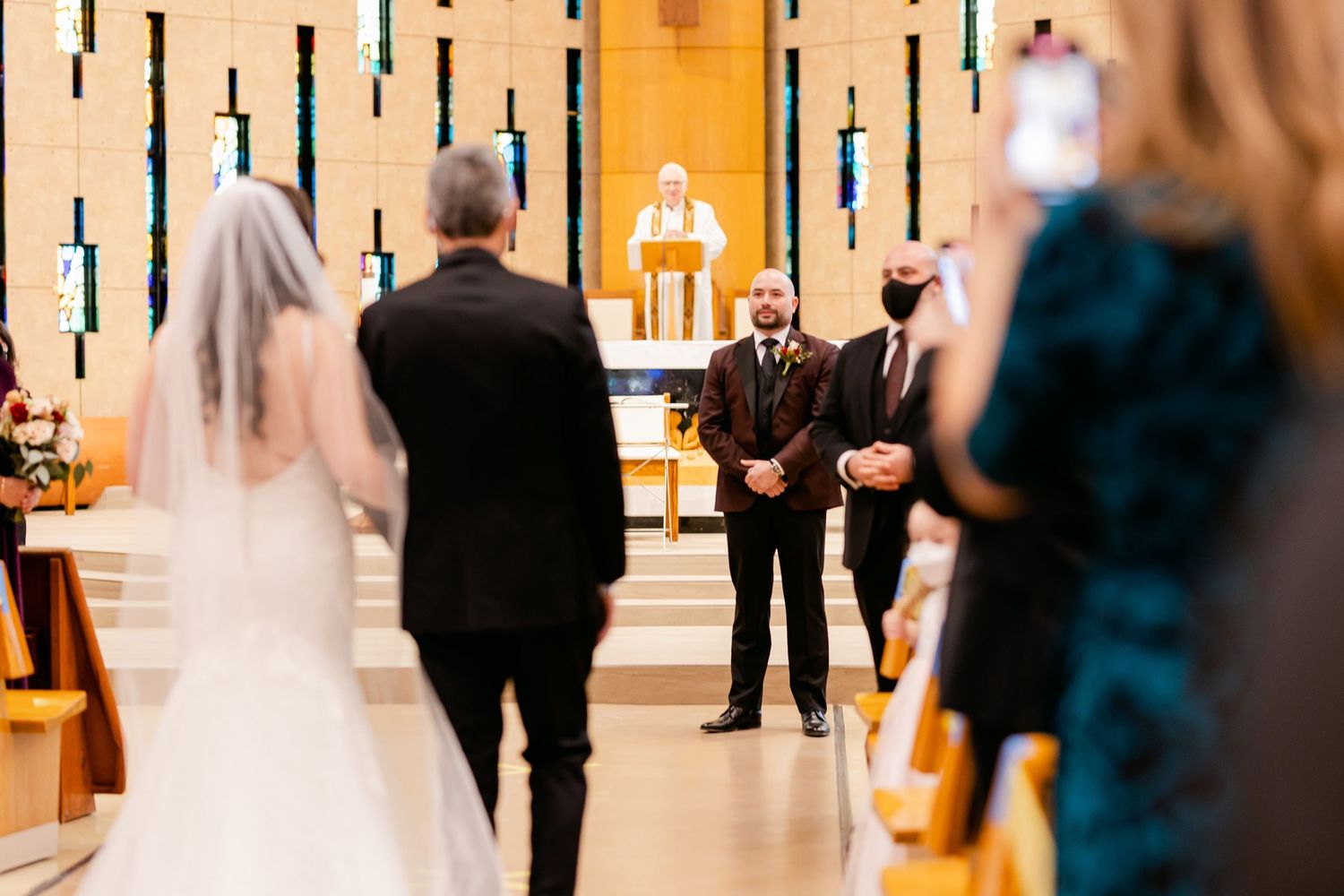Wedding processional in modern church sanctuary with decorative wall lighting.