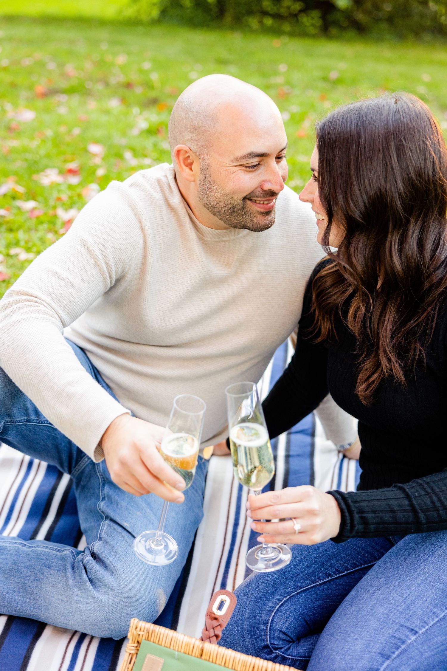 Romantic moment shared between couple during champagne picnic in park.