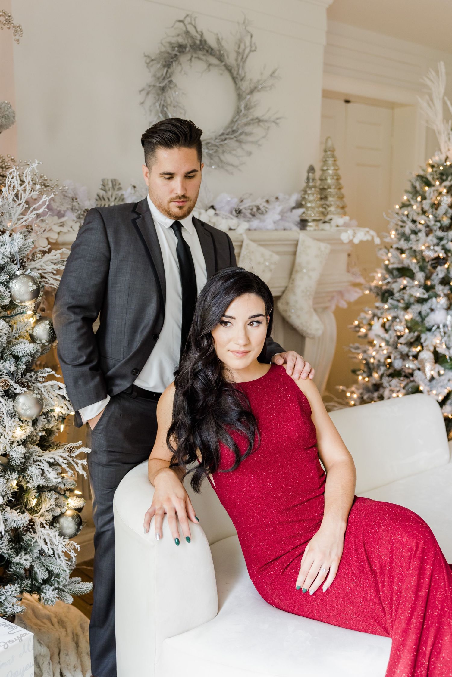 Fashion photoshoot with red gown and dark suit against a winter wonderland backdrop.