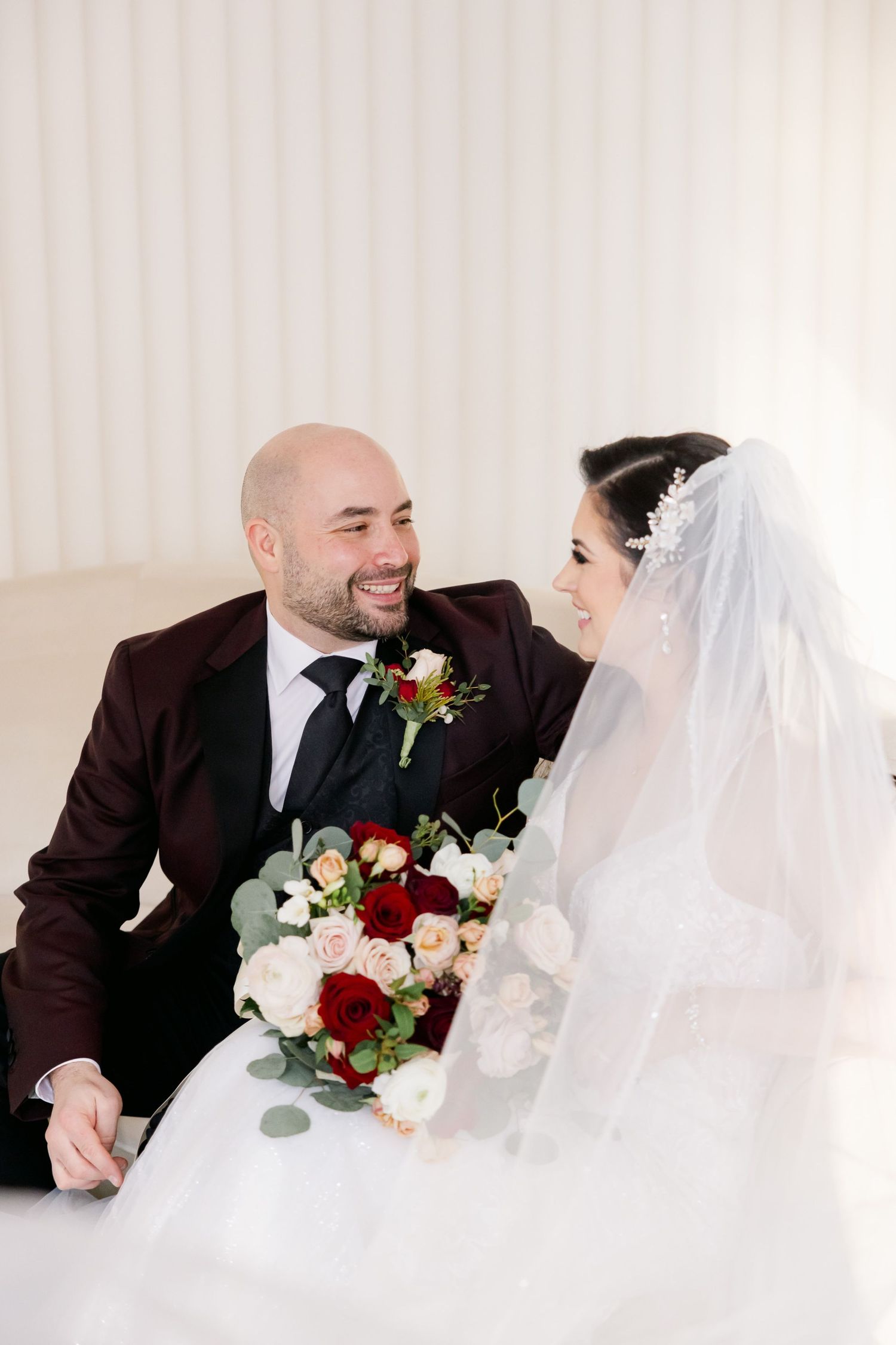 Intimate moment between couple sharing laughter during wedding portraits.