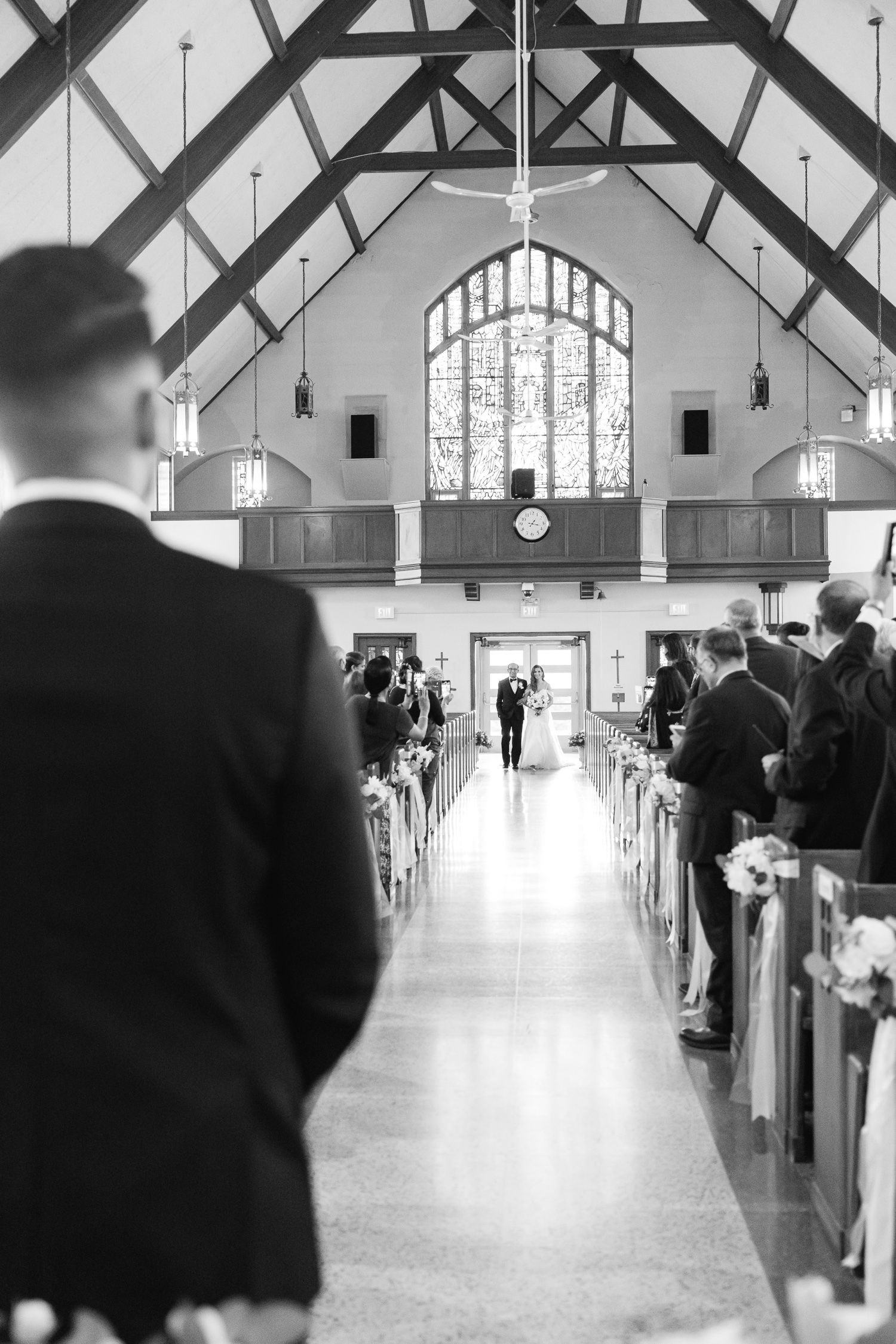 A black and white photo of a church wedding ceremony with dramatic vaulted ceilings and stained glass windows.