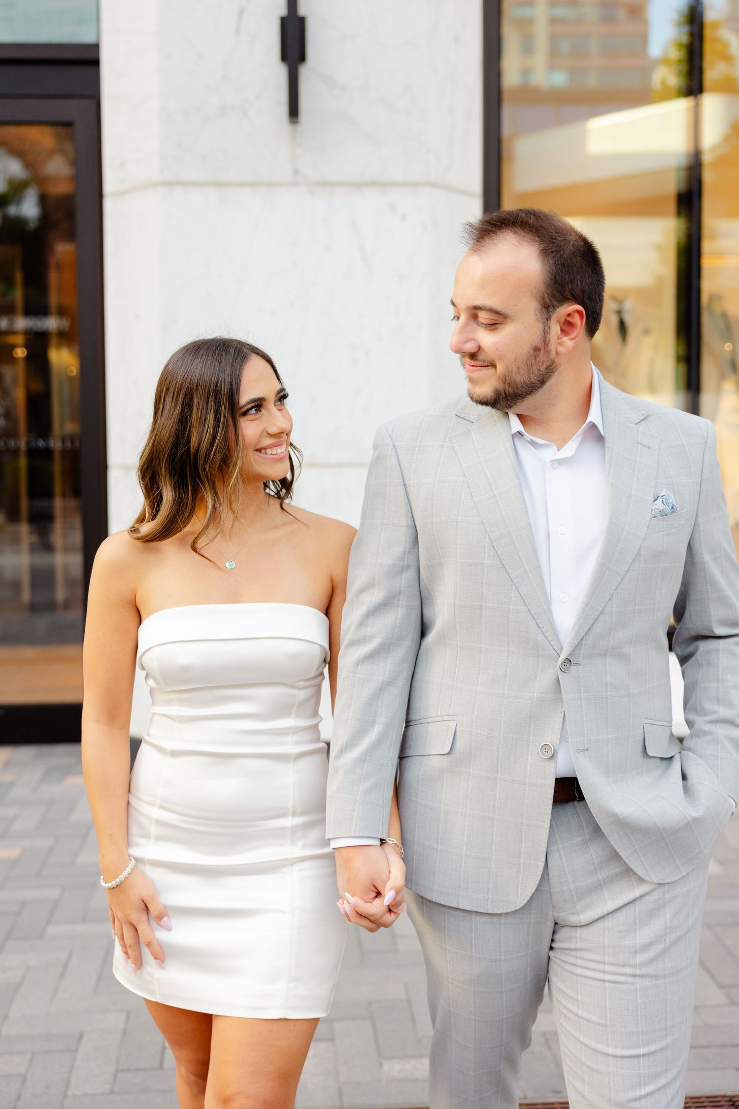 Stylish pair share romantic moment in front of luxury retail storefront.