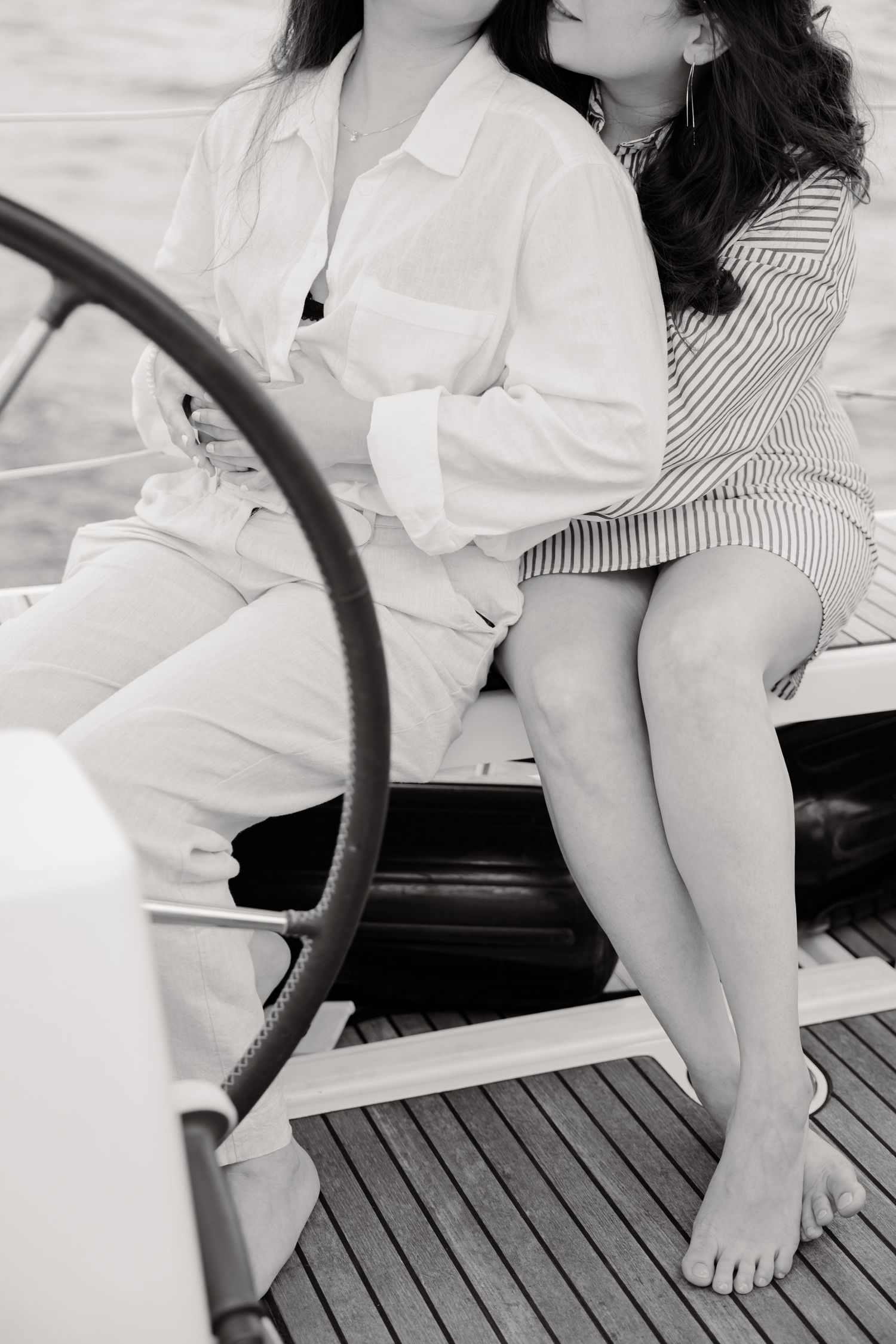 Black and white photo showing casual summer attire and bare feet on a yacht's wooden deck.