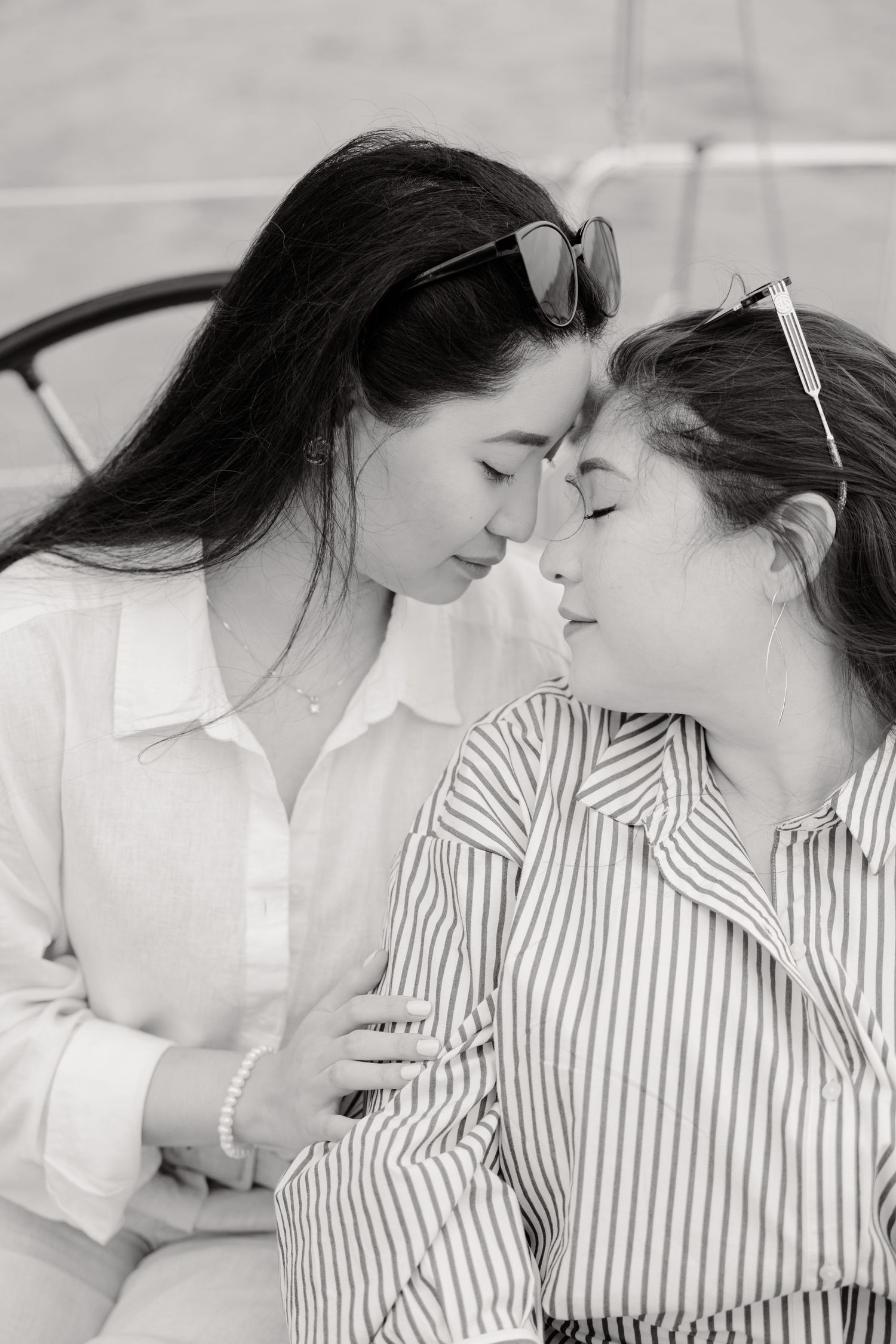 A black and white portrait of two people in close embrace on a boat wearing contrasting striped and white shirts.