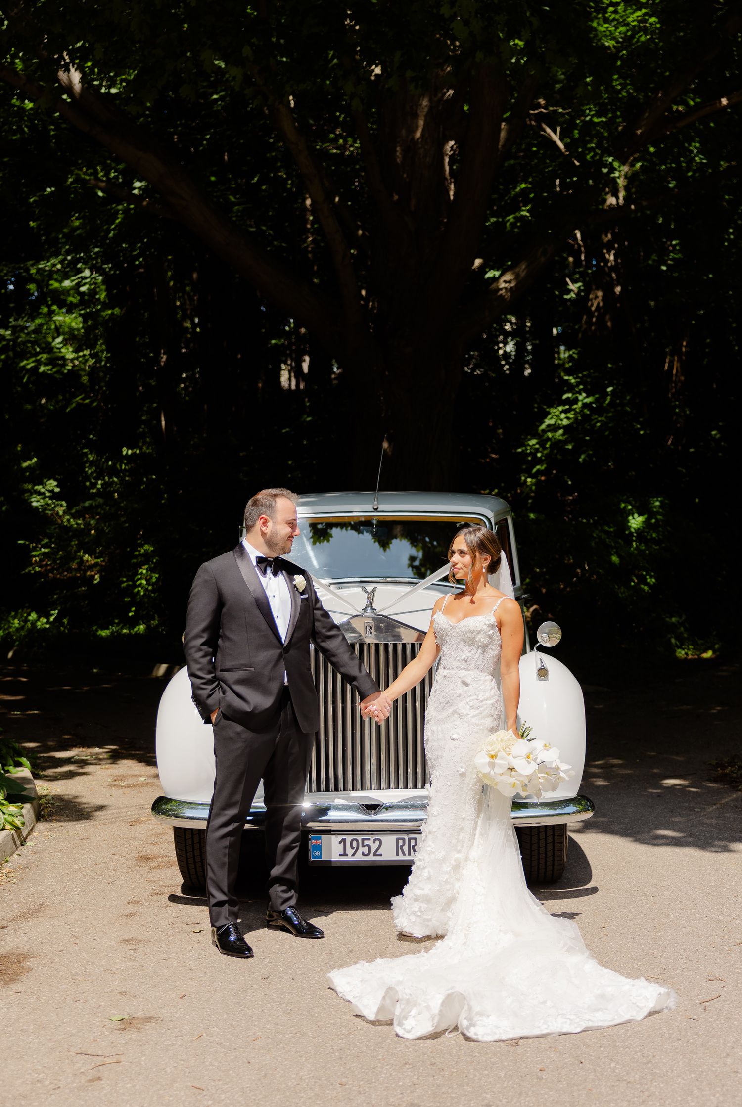 A series of wedding photos showing a couple posing with a classic white Rolls-Royce on a sunny, tree-lined path.