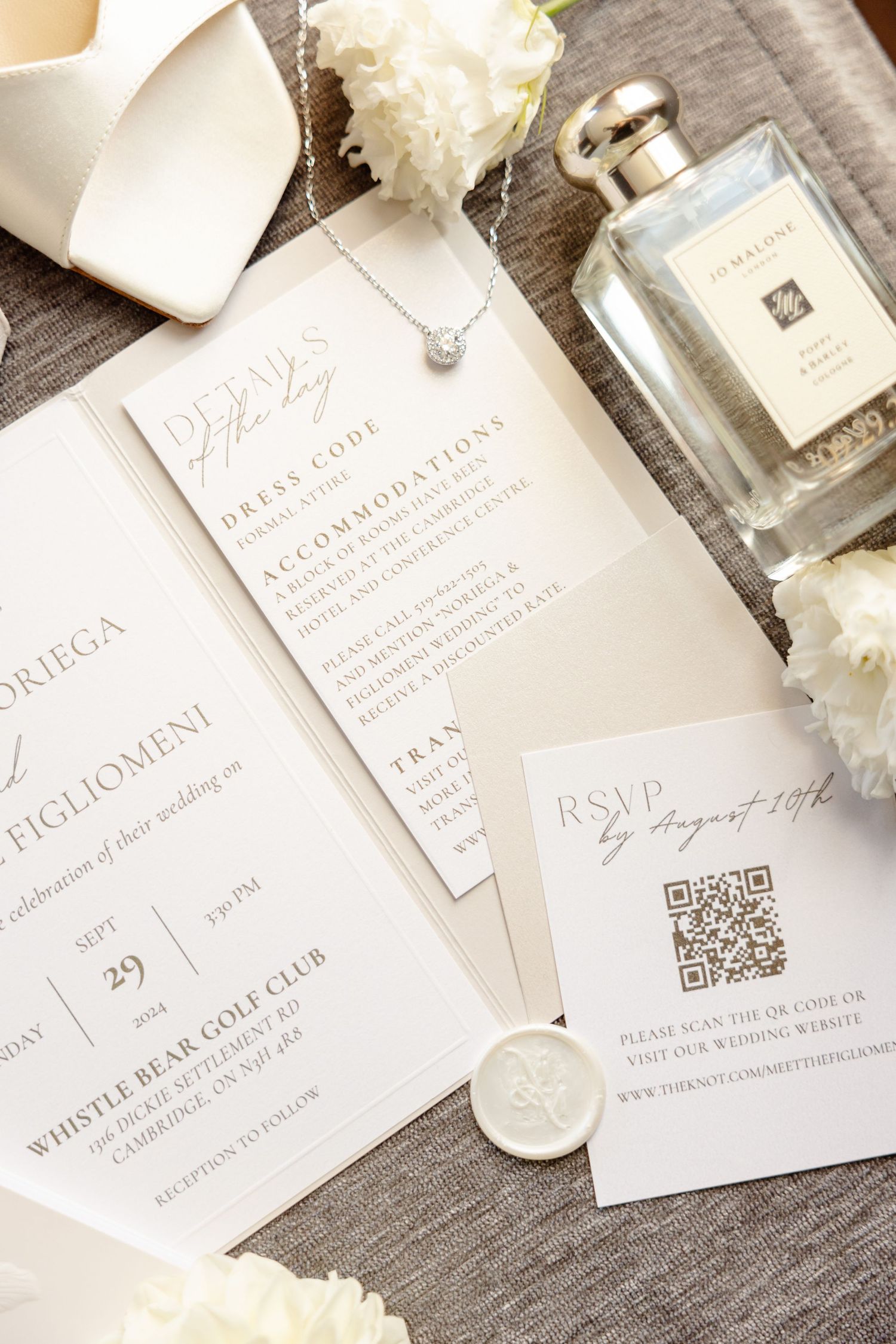 Wedding invitation suite with Jo Malone perfume and white floral accents on wooden surface.