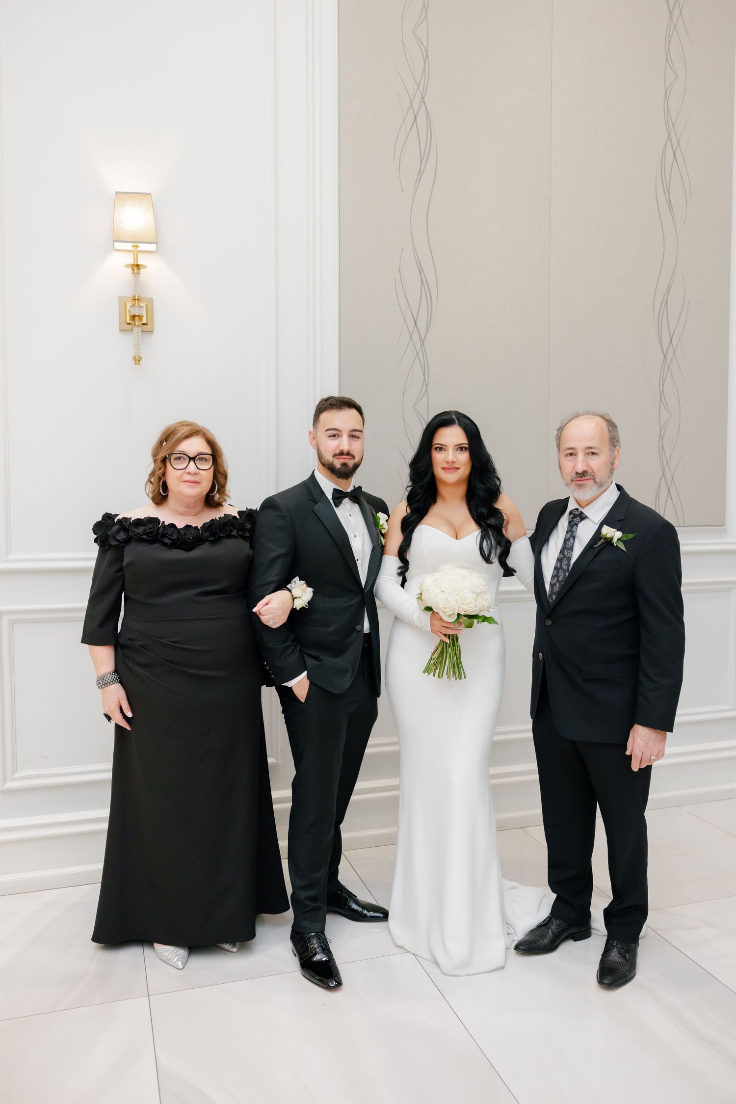 Formal wedding party photo with bride and family members in elegant venue.