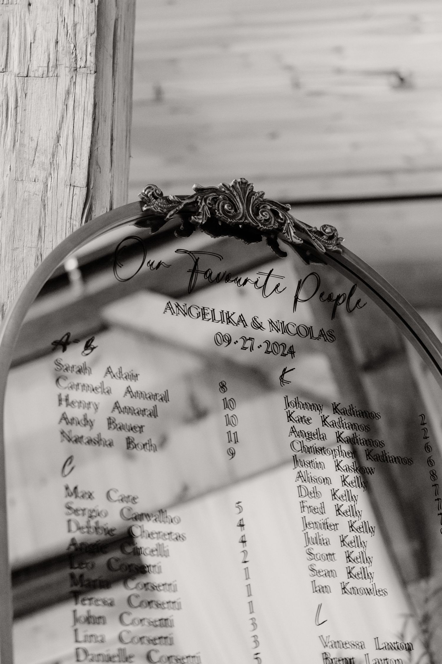 Black and white close-up of wedding seating chart with ornate frame detail.