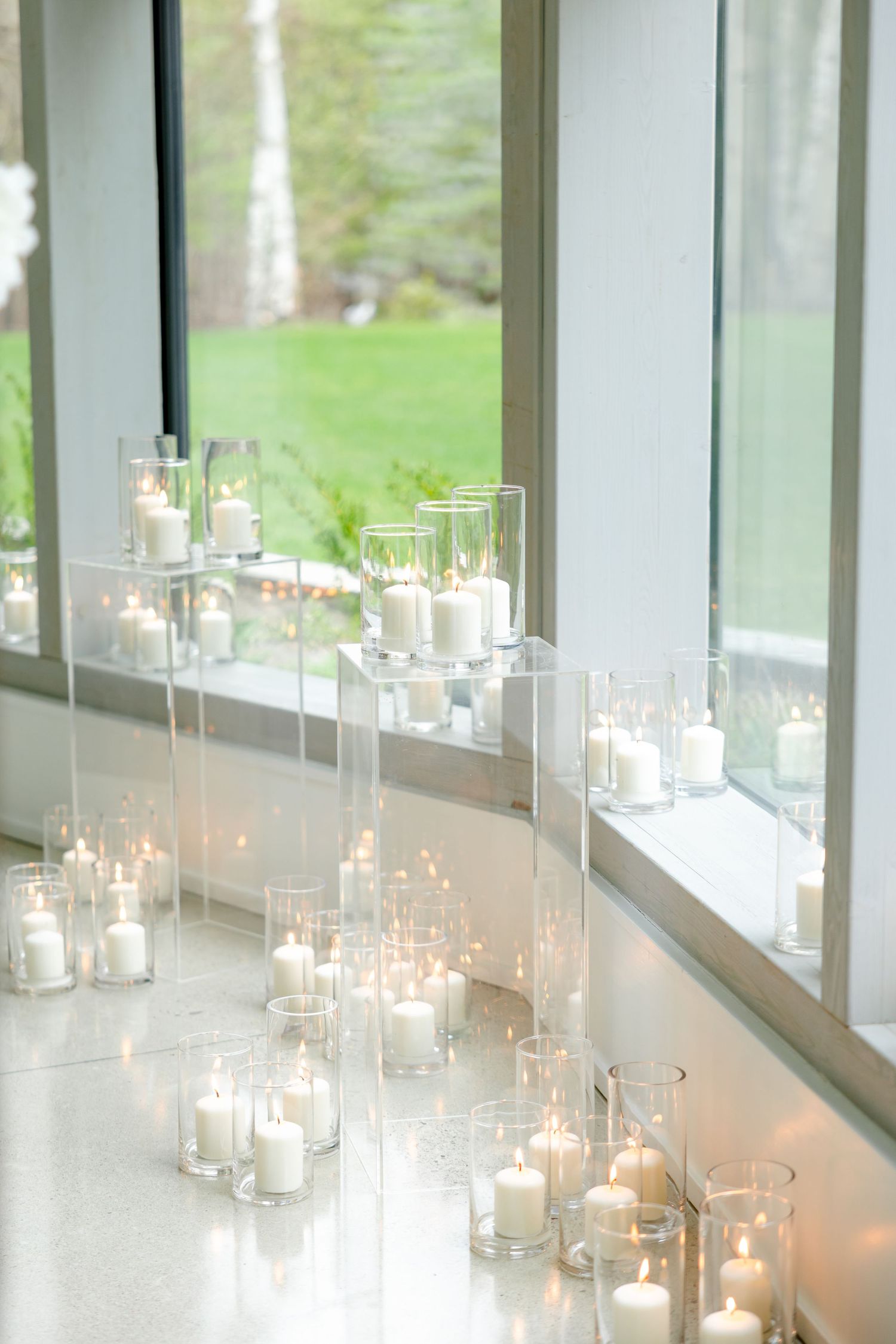 Row of glowing candles in glass holders along windowsill creating romantic ambiance.