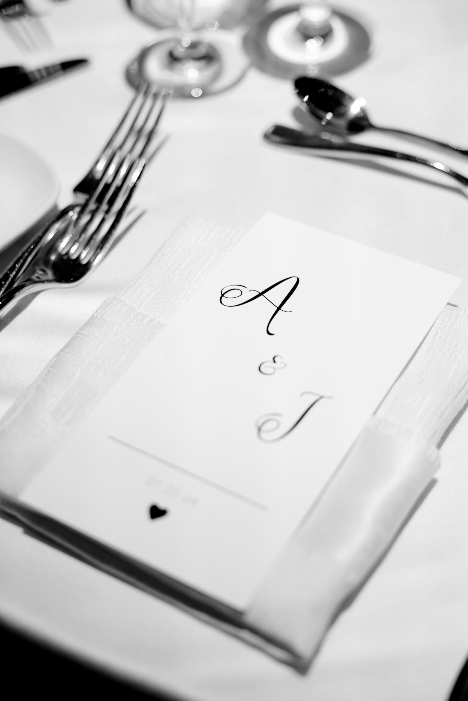 Black and white photo of wedding place setting with monogrammed card.