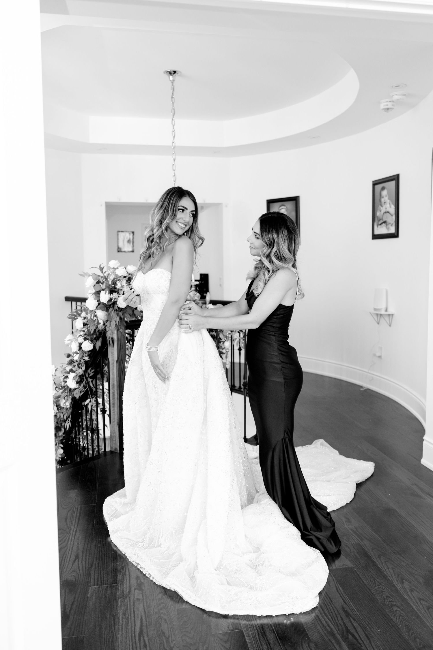 Black and white photo of wedding dress preparations with elegant dresses and hardwood floors.
