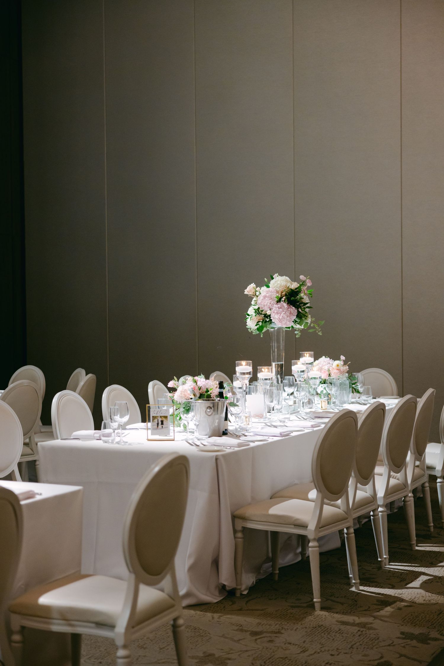 Sophisticated dining setup with white oval-back chairs and delicate floral centerpieces.