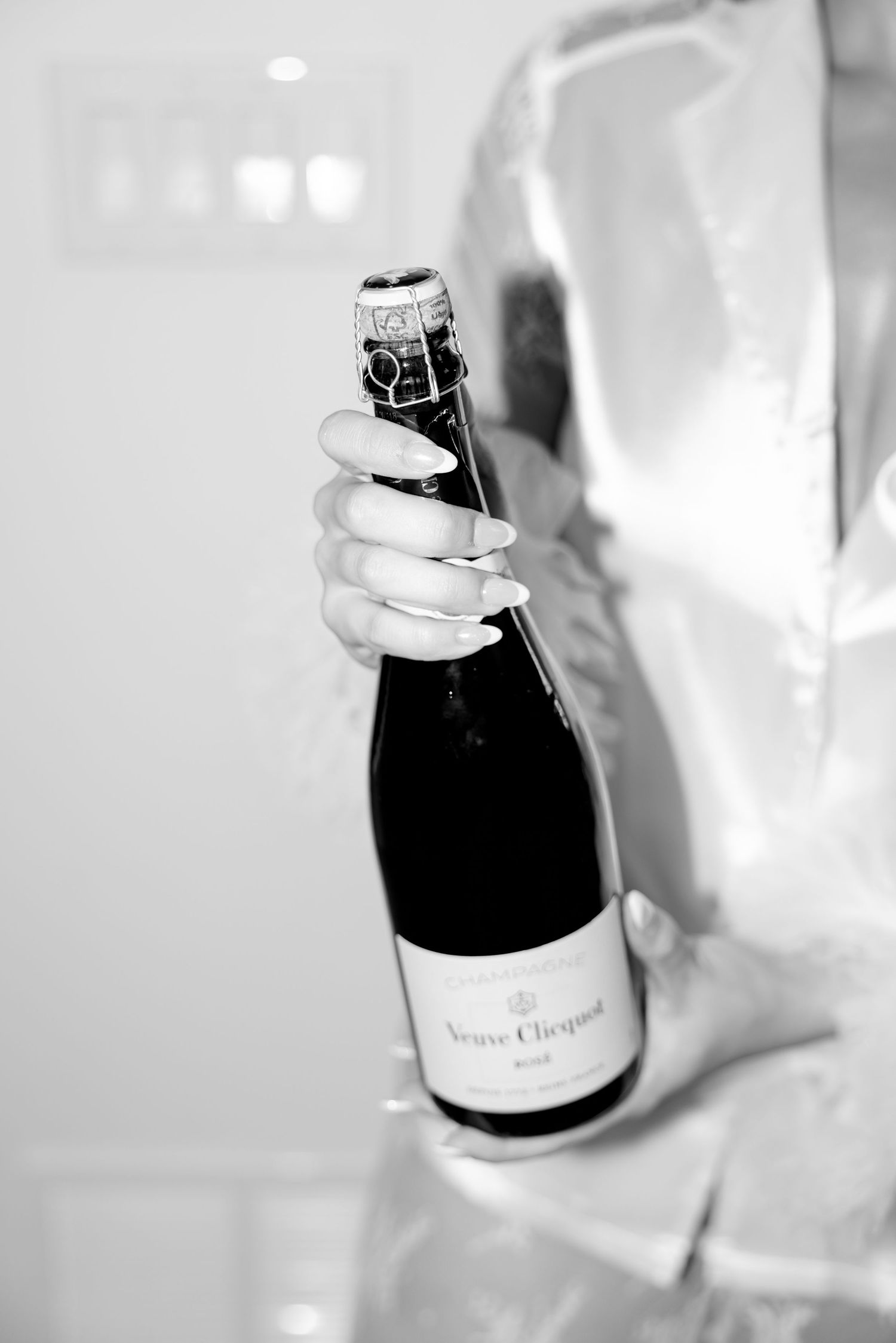 Black and white image of Veuve Clicquot champagne bottle being held.