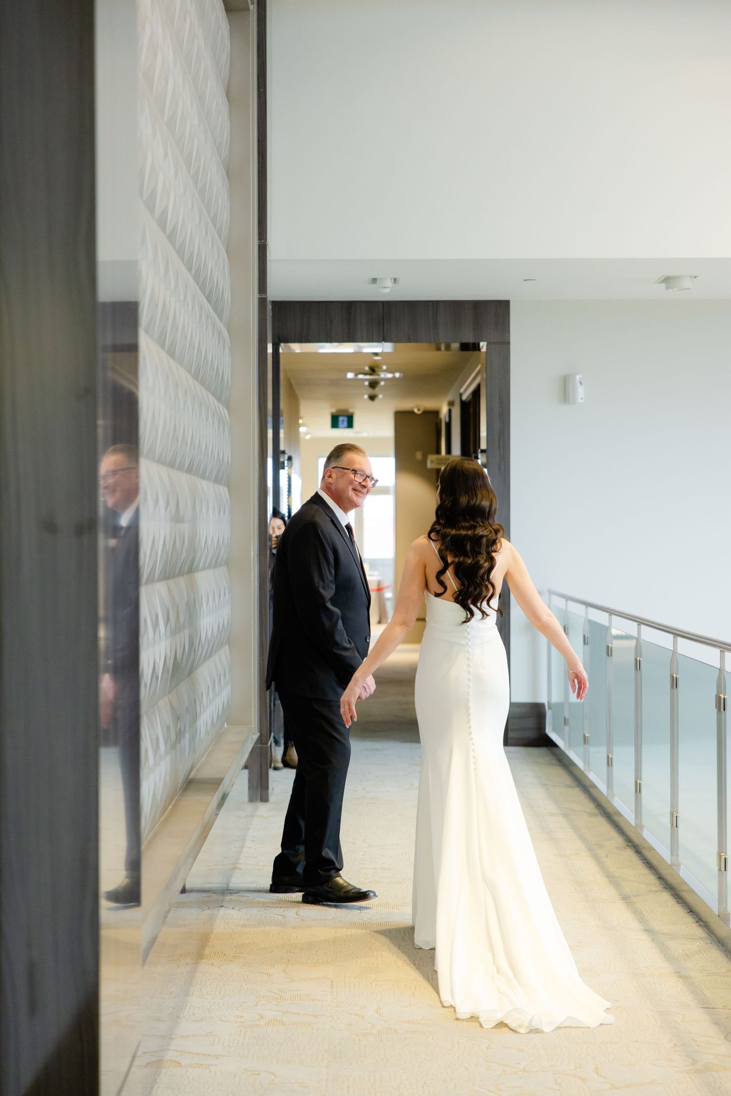 A couple shares a tender moment in a modern hallway with textured wall panels.
