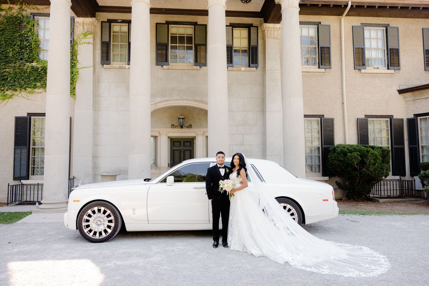 Elegant wedding scene with white Rolls Royce and classical columned building.