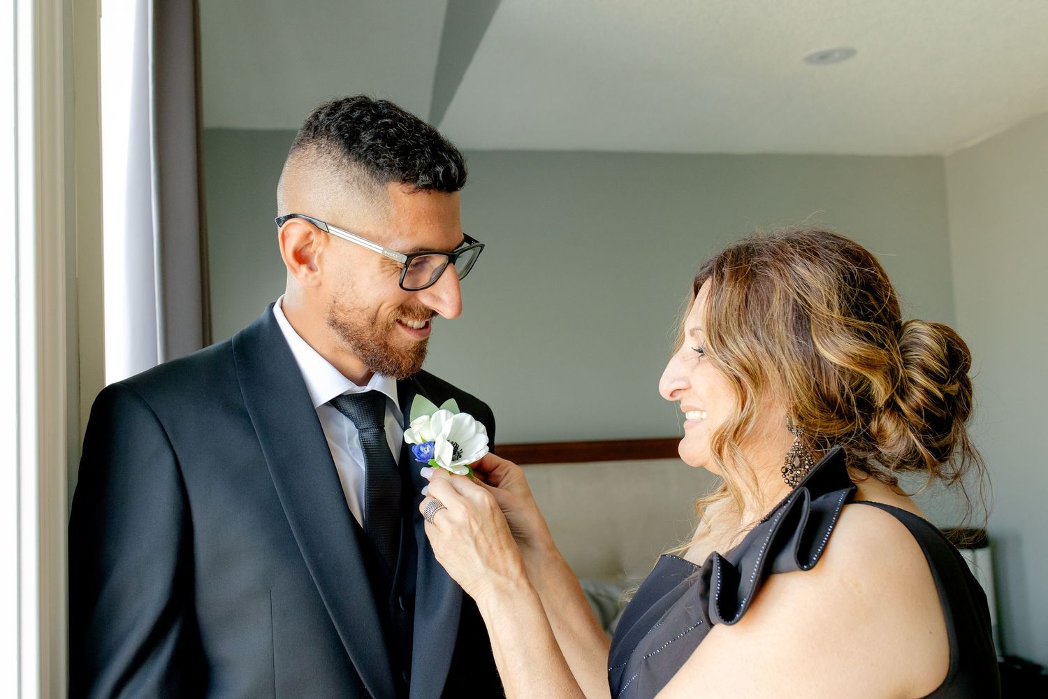 A heartwarming moment as a boutonniere is pinned on during wedding preparations.