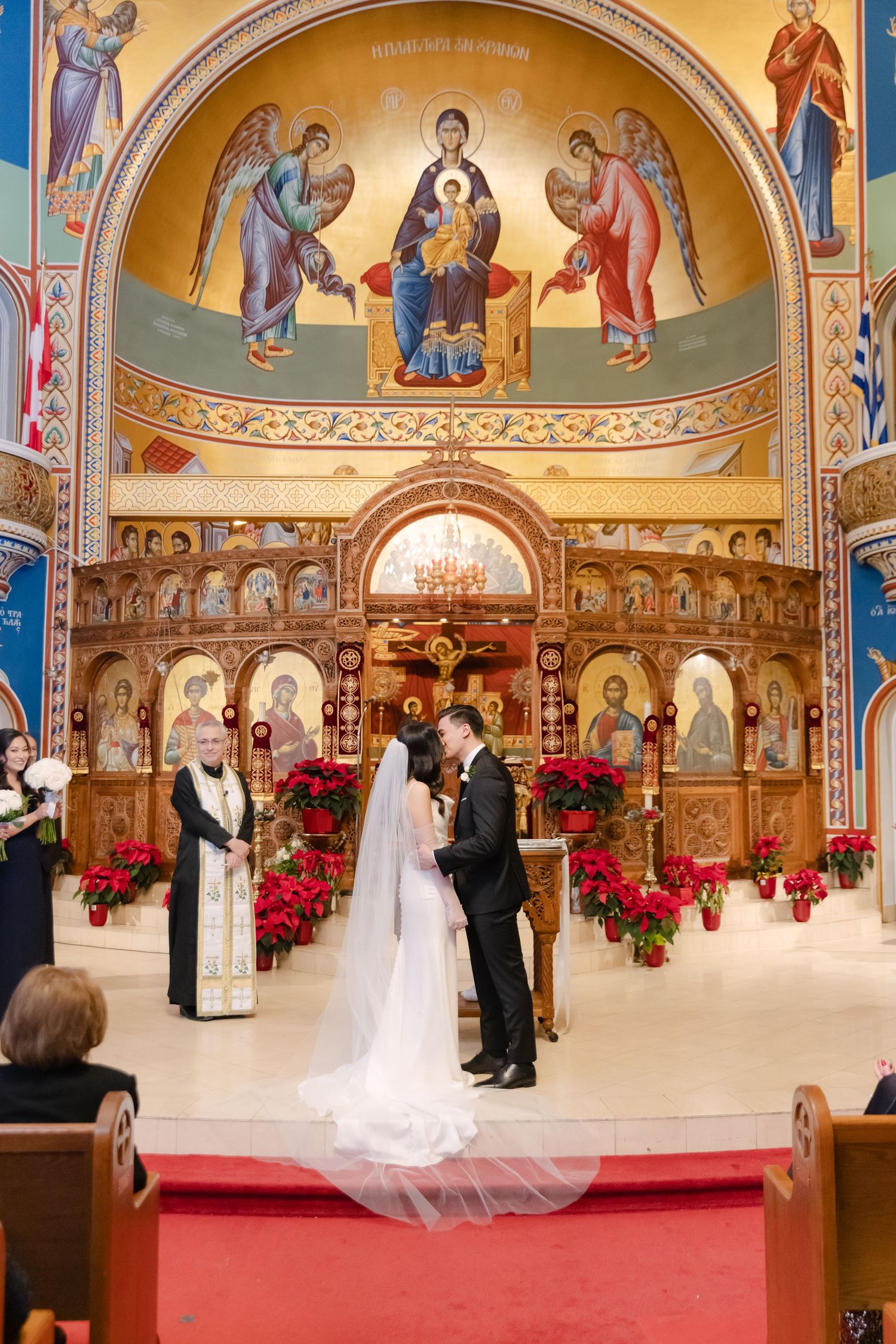 Wedding ceremony under beautiful Byzantine-style church dome with religious frescoes and floral decorations.