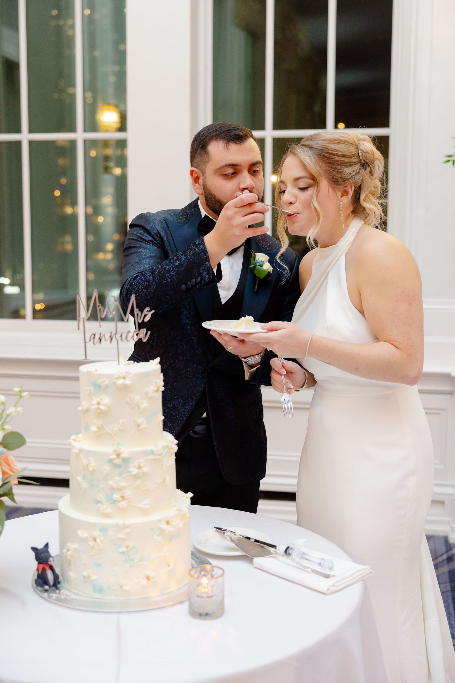 Couple shares wedding cake moment at elegant reception with blue and white tiered cake.