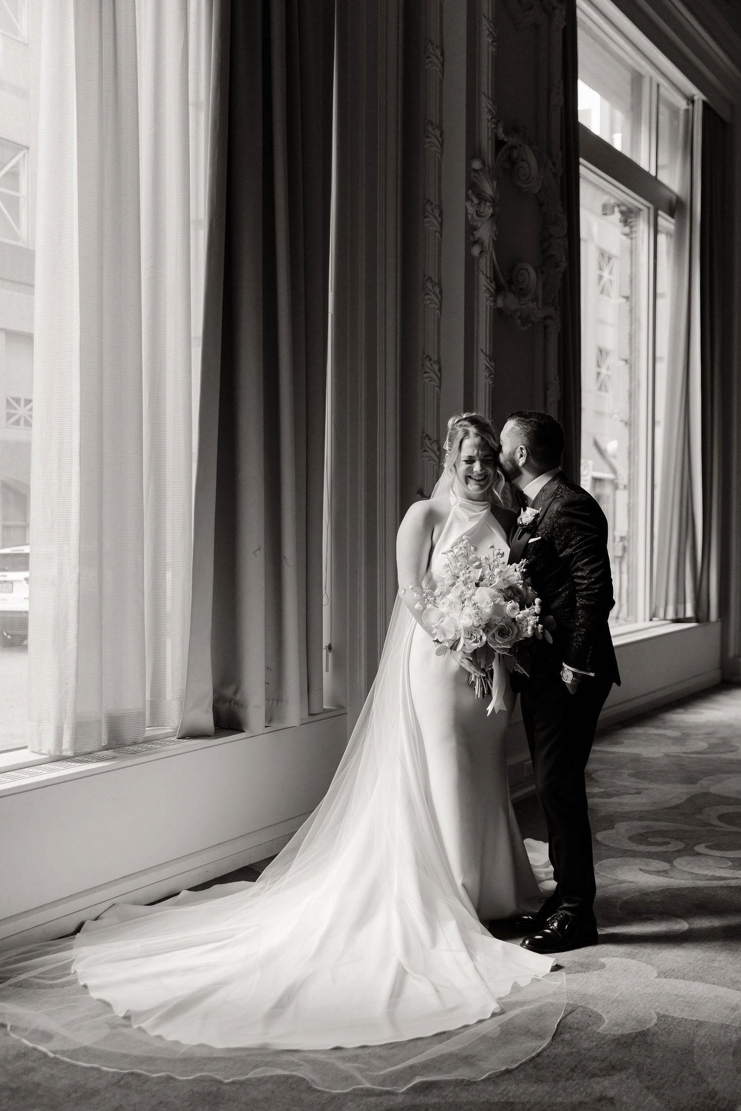 A romantic black and white wedding photo series showing a couple in an elegant corridor with flowing white dress train.