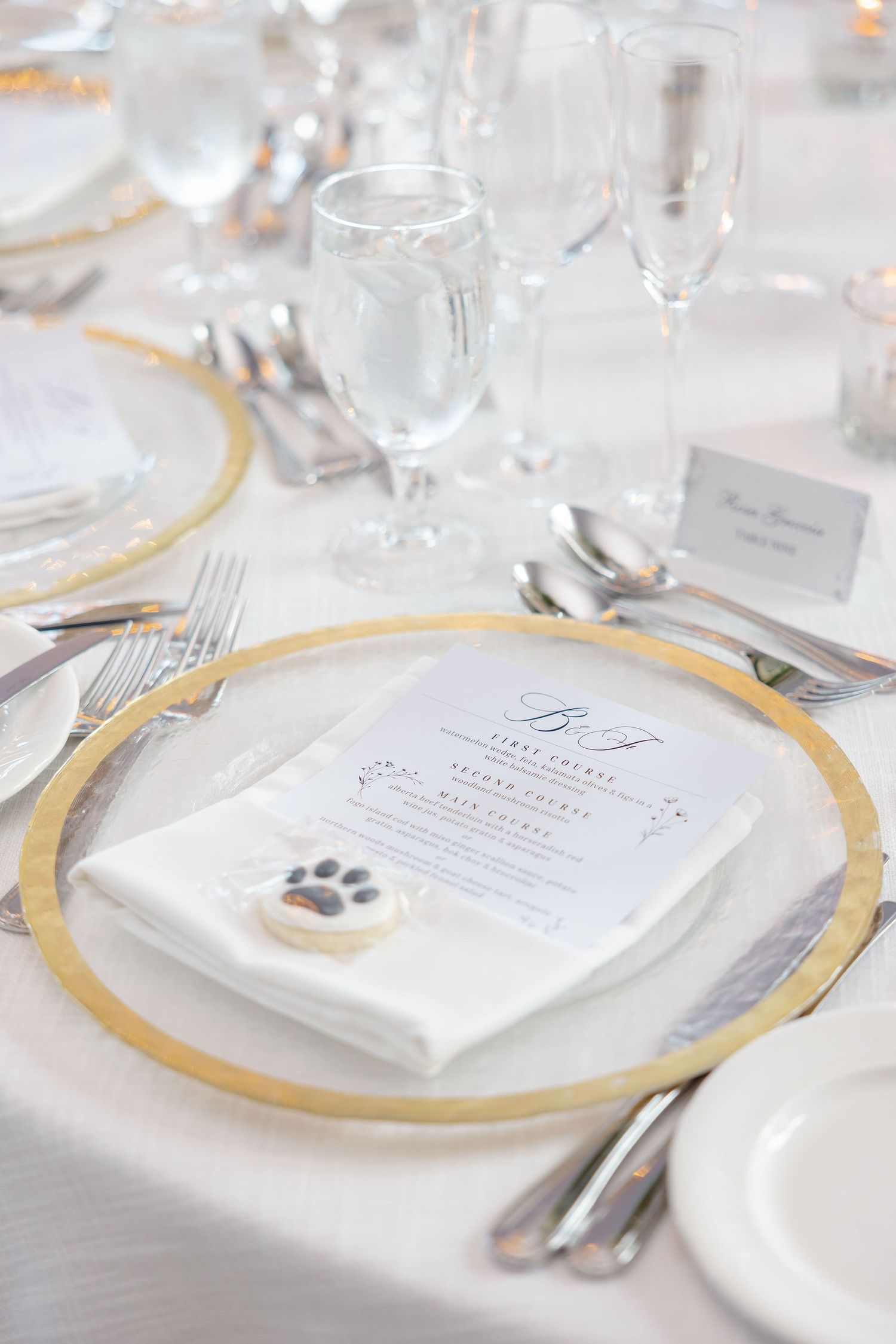 Elegant wedding place settings with gold-rimmed plates, crystal glassware, and menu cards on white tablecloths.