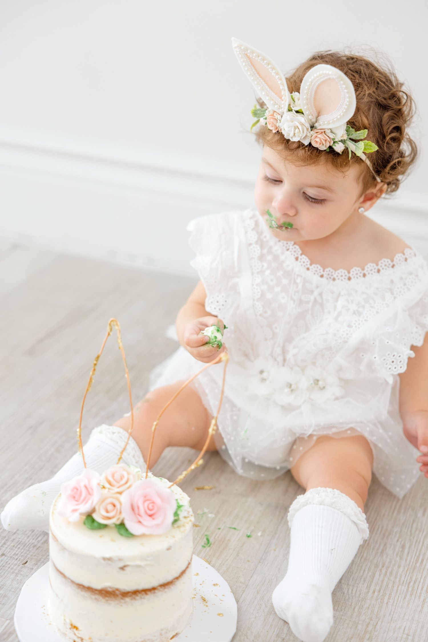 Ethereal spring photoshoot featuring delicate cake decorations and floral bunny ear crown.