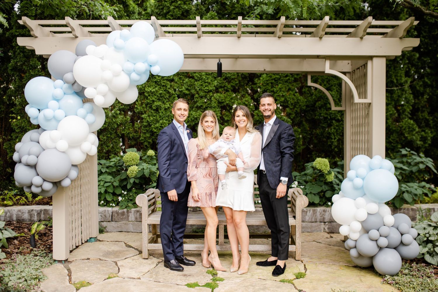 Elegant outdoor event under white pergola decorated with blue and white balloon garland.