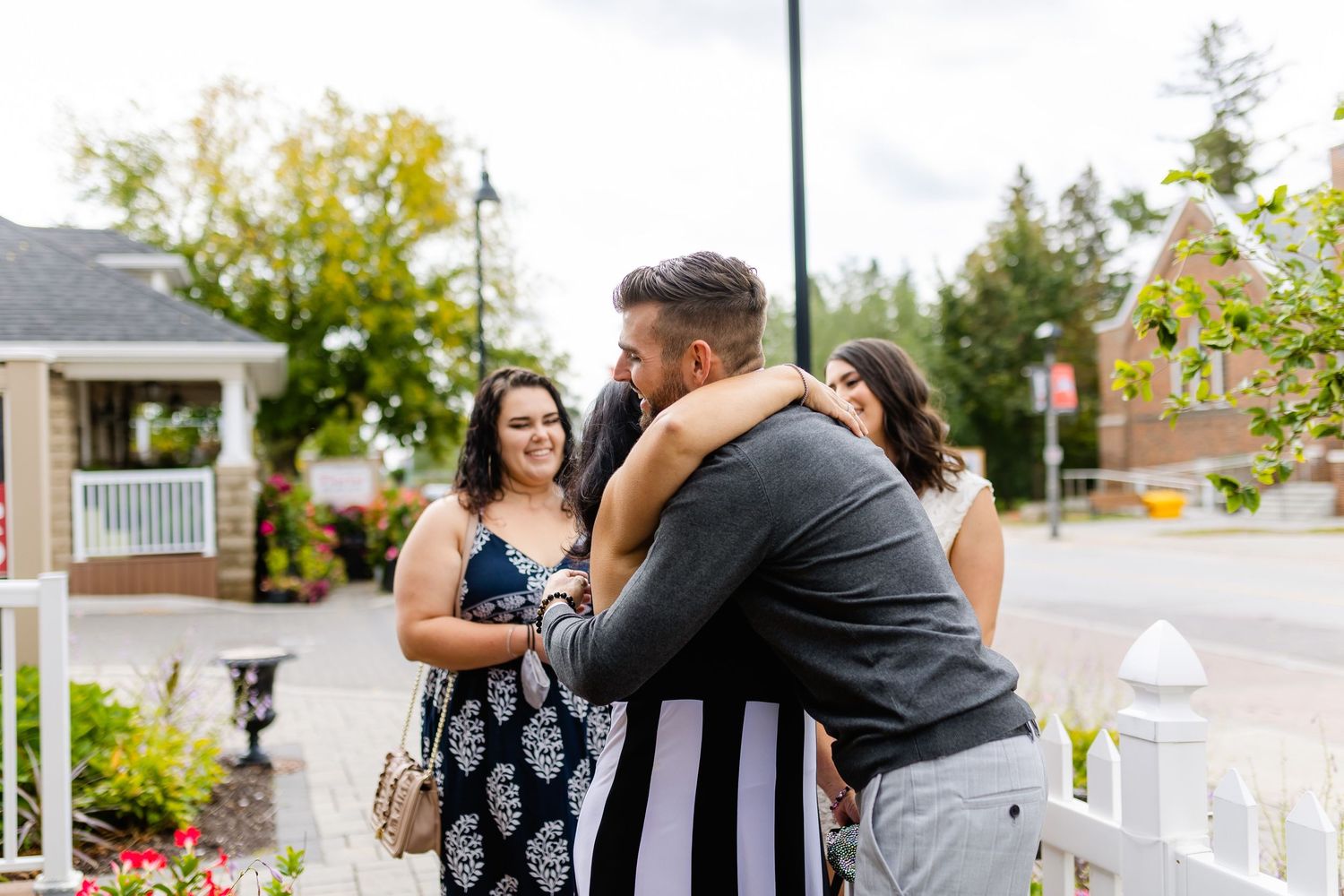 A group of friends sharing hugs and warm embraces on a porch with garden views.